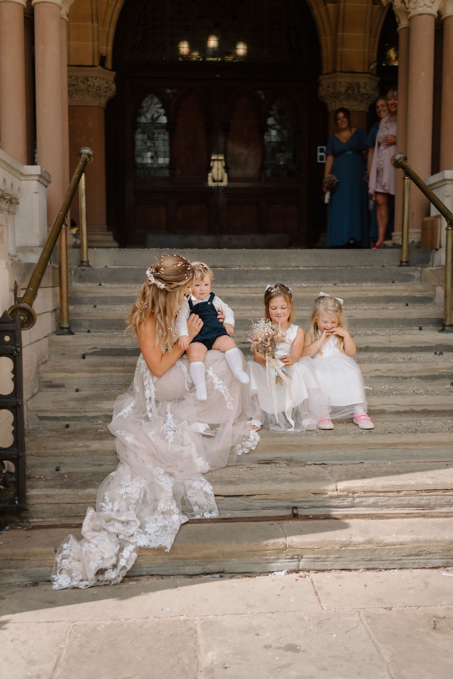 Sweet moment between bride and young attendants on church steps during wedding celebration in Northampton.