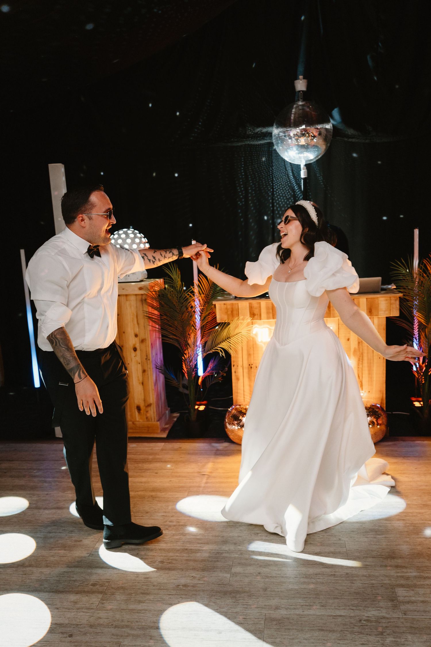 Bride and groom share first dance under disco ball lights at elegant wedding reception venue.