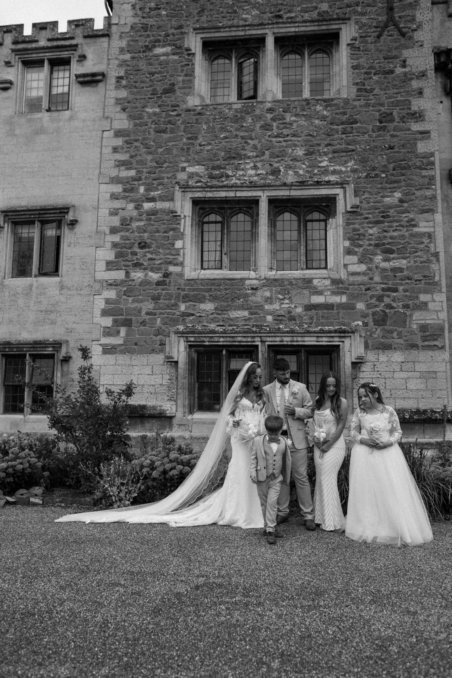 Wedding party poses against historic stone building facade in progressively spaced dramatic shots.