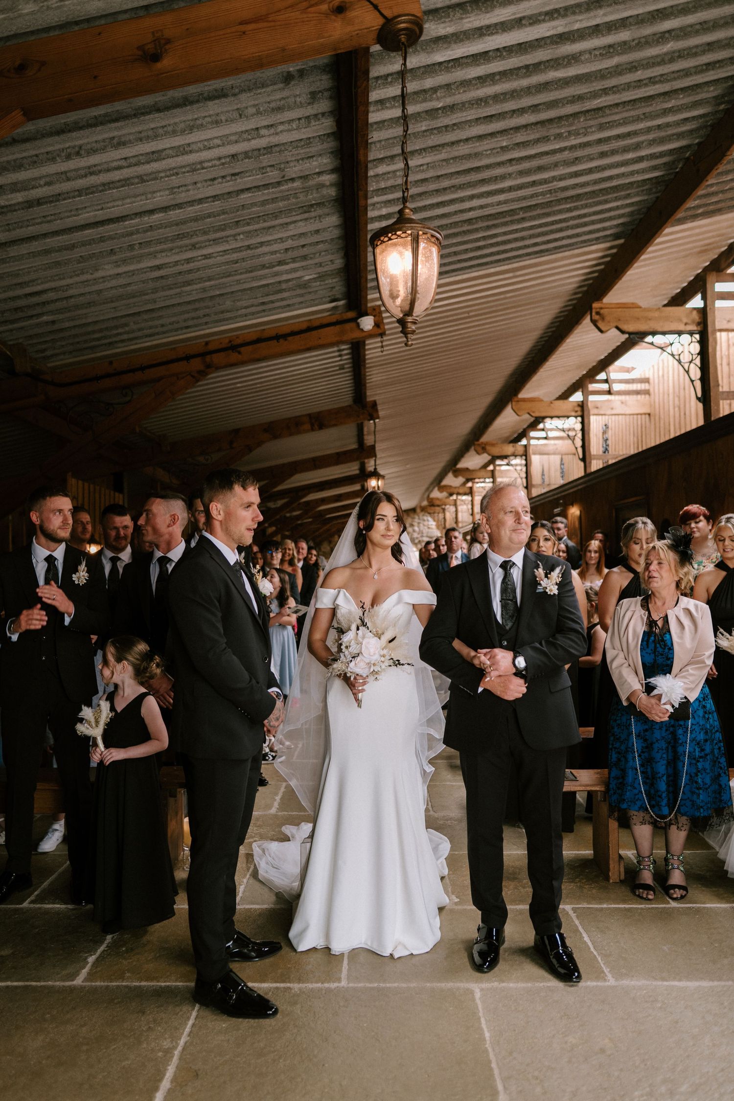 Traditional wedding ceremony in a rustic indoor venue with wooden beams and pendant lighting.
