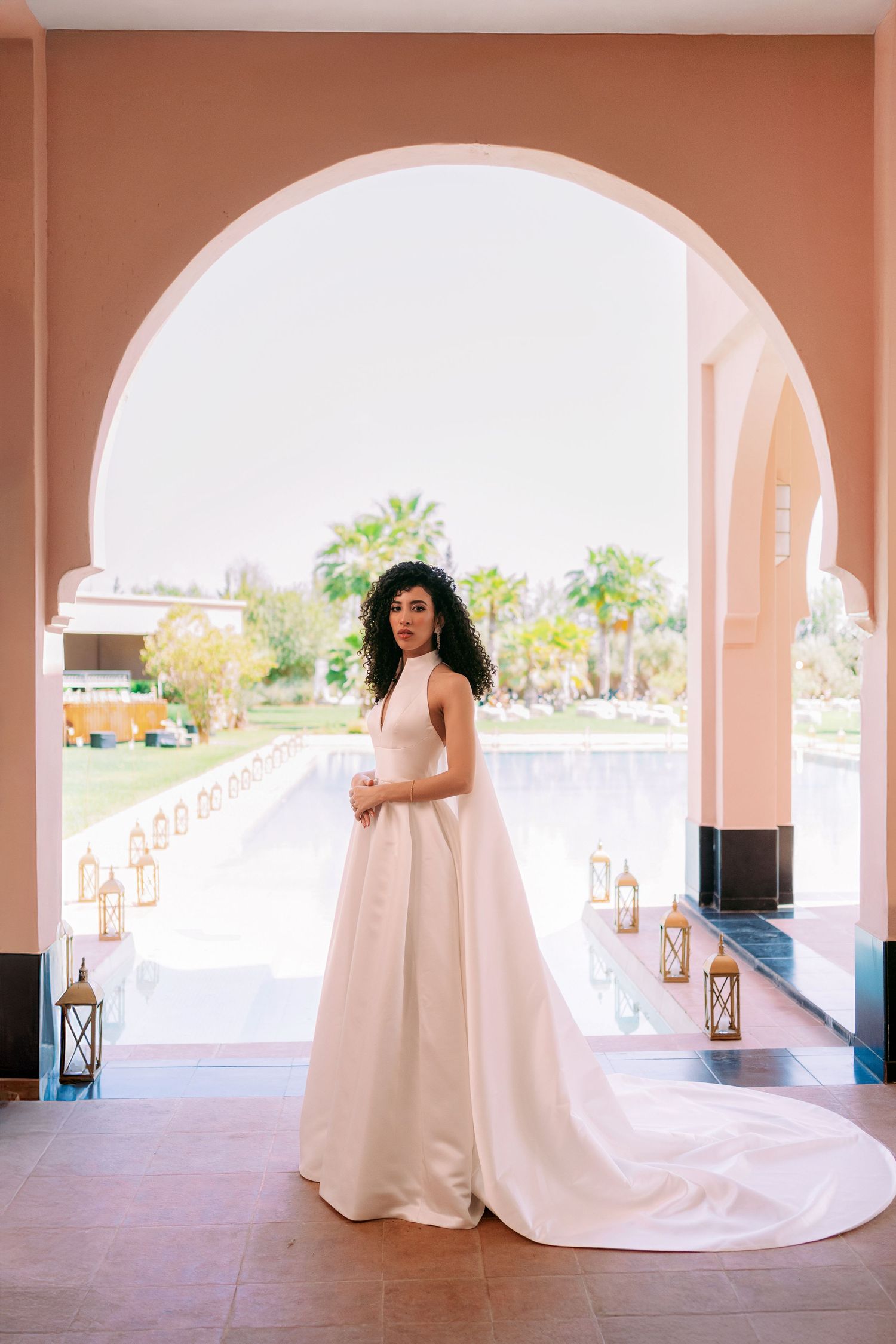 Elegant bridal portraits in a peach-colored archway with flowing white gown.