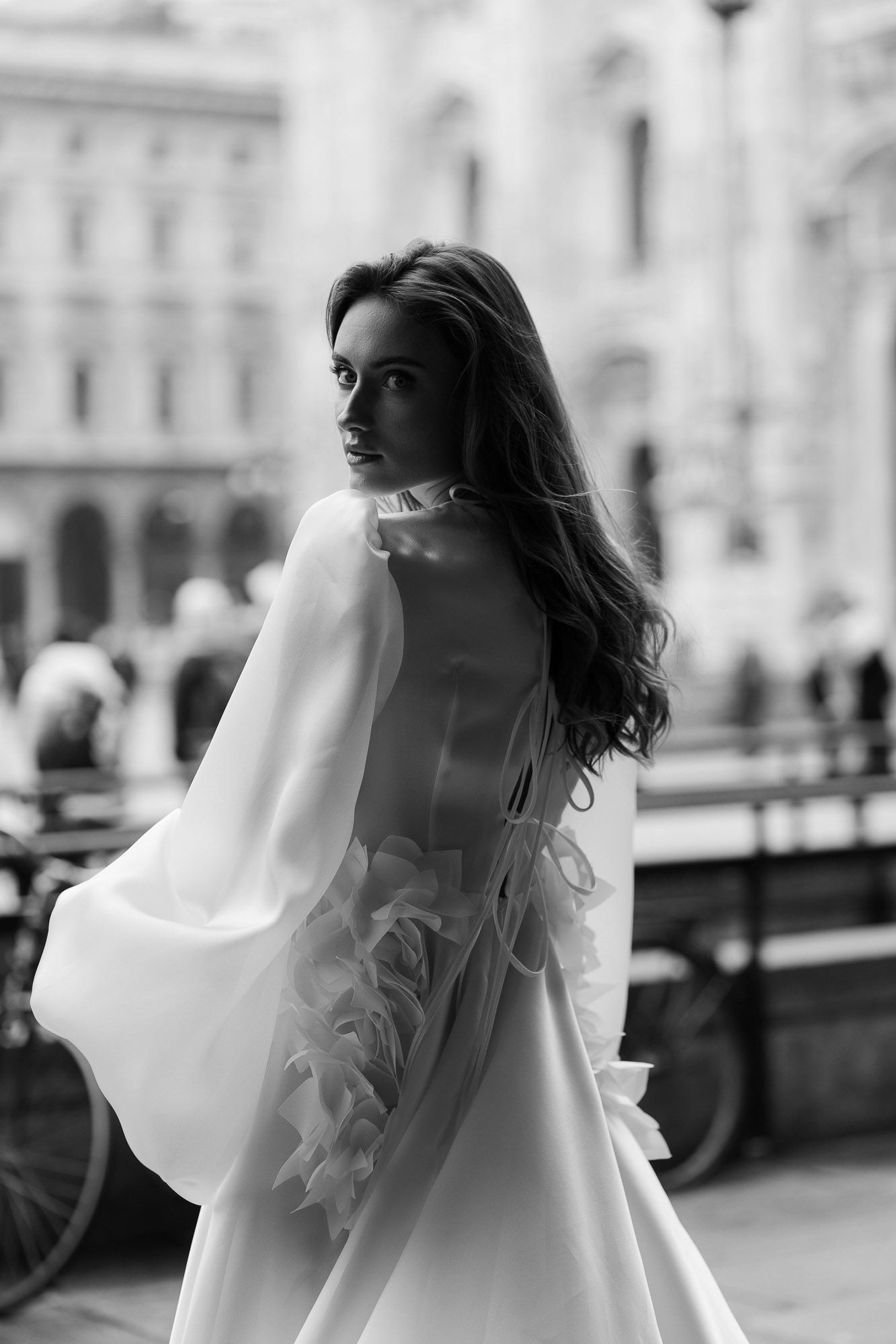 A black and white artistic sequence showing a bride in a flowing wedding dress twirling on a city street.