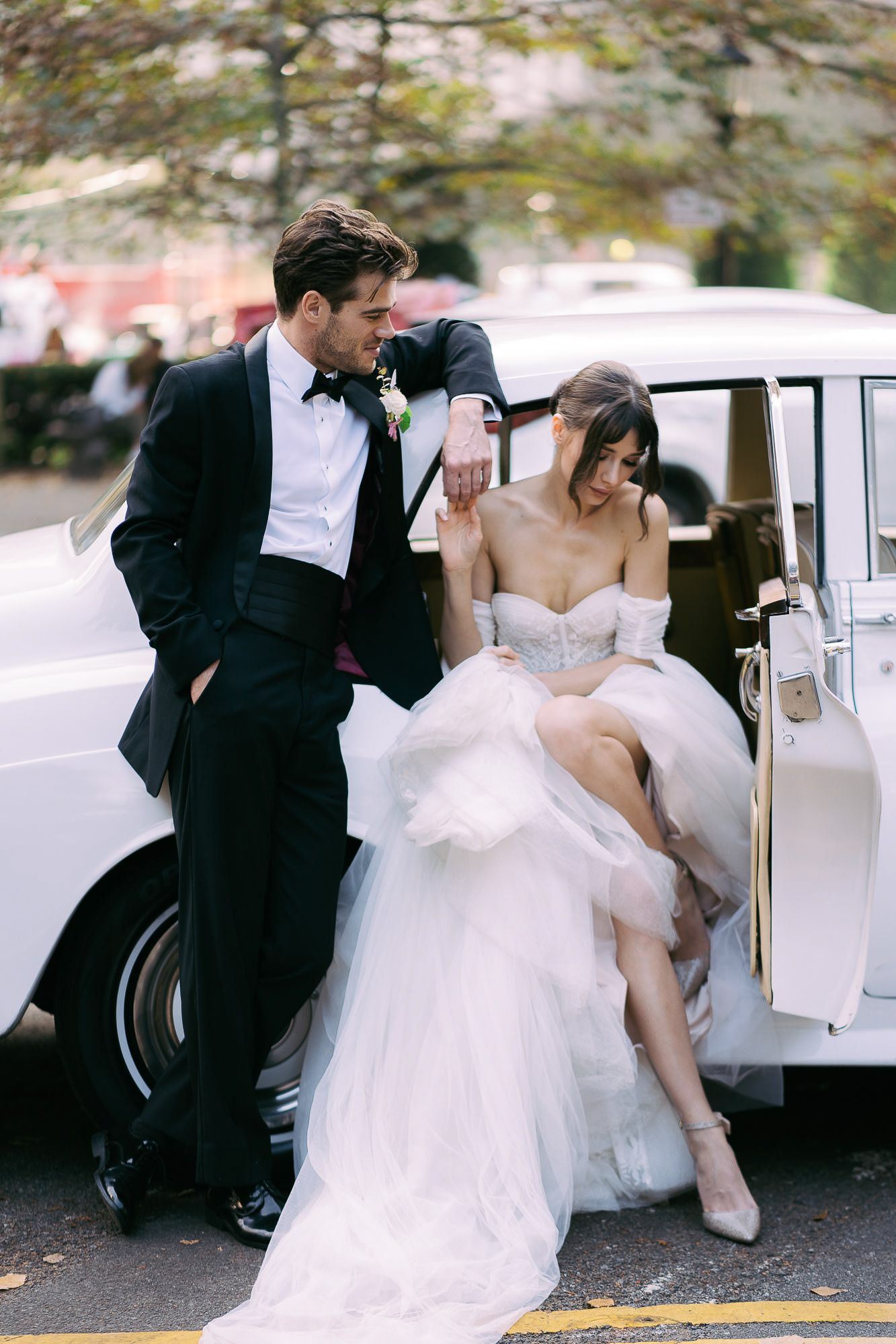 A romantic wedding couple shares intimate moments next to a vintage car during their outdoor photo session.
