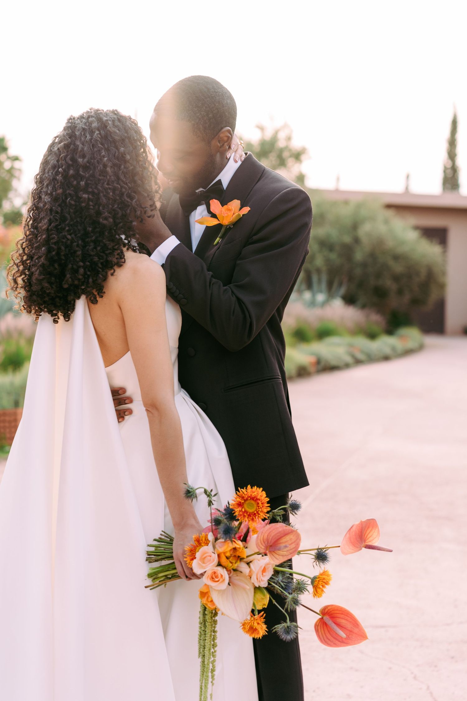 Wedding couple with orange sunflower bouquet in an intimate outdoor portrait session.