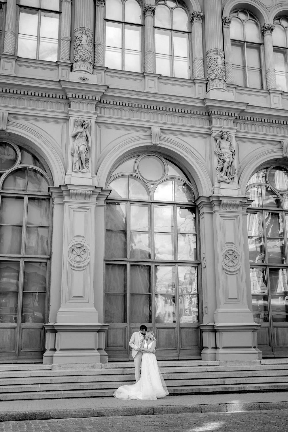 A black and white photo series of a bride in a wedding dress posing in front of an ornate historic building facade.