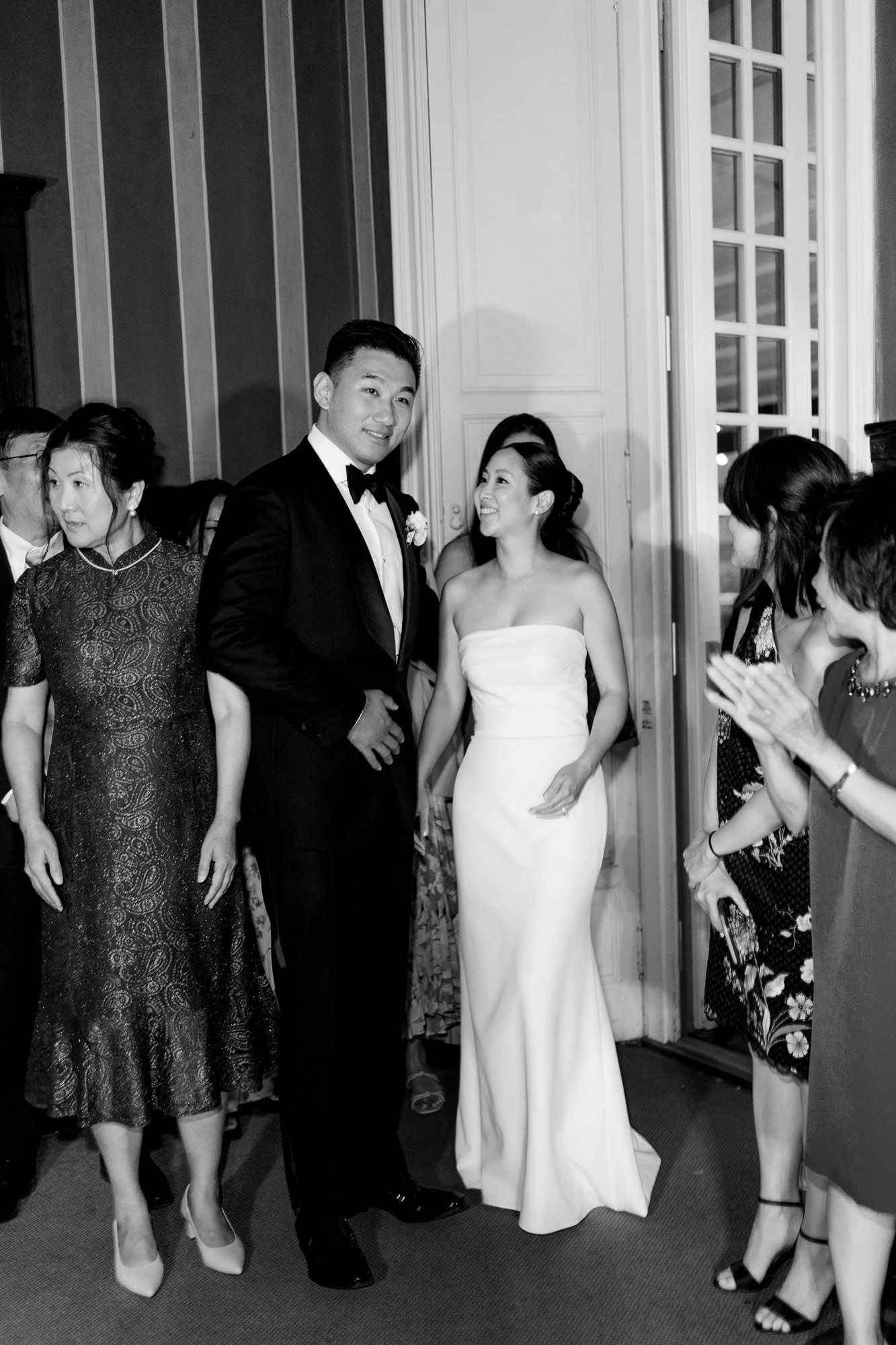 A black and white photo series showing wedding guests in formal attire dancing and socializing at an elegant reception.