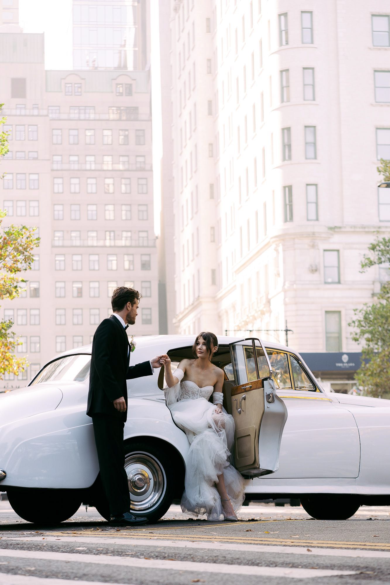 A sequence of wedding photos showing a couple getting into a classic white vintage car on their special day.
