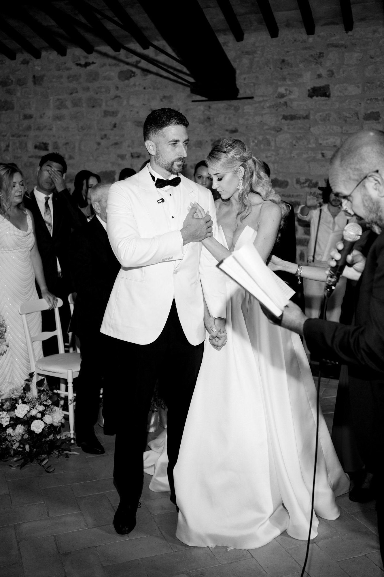 A couple shares a romantic dance at their wedding reception in a rustic brick-walled venue.