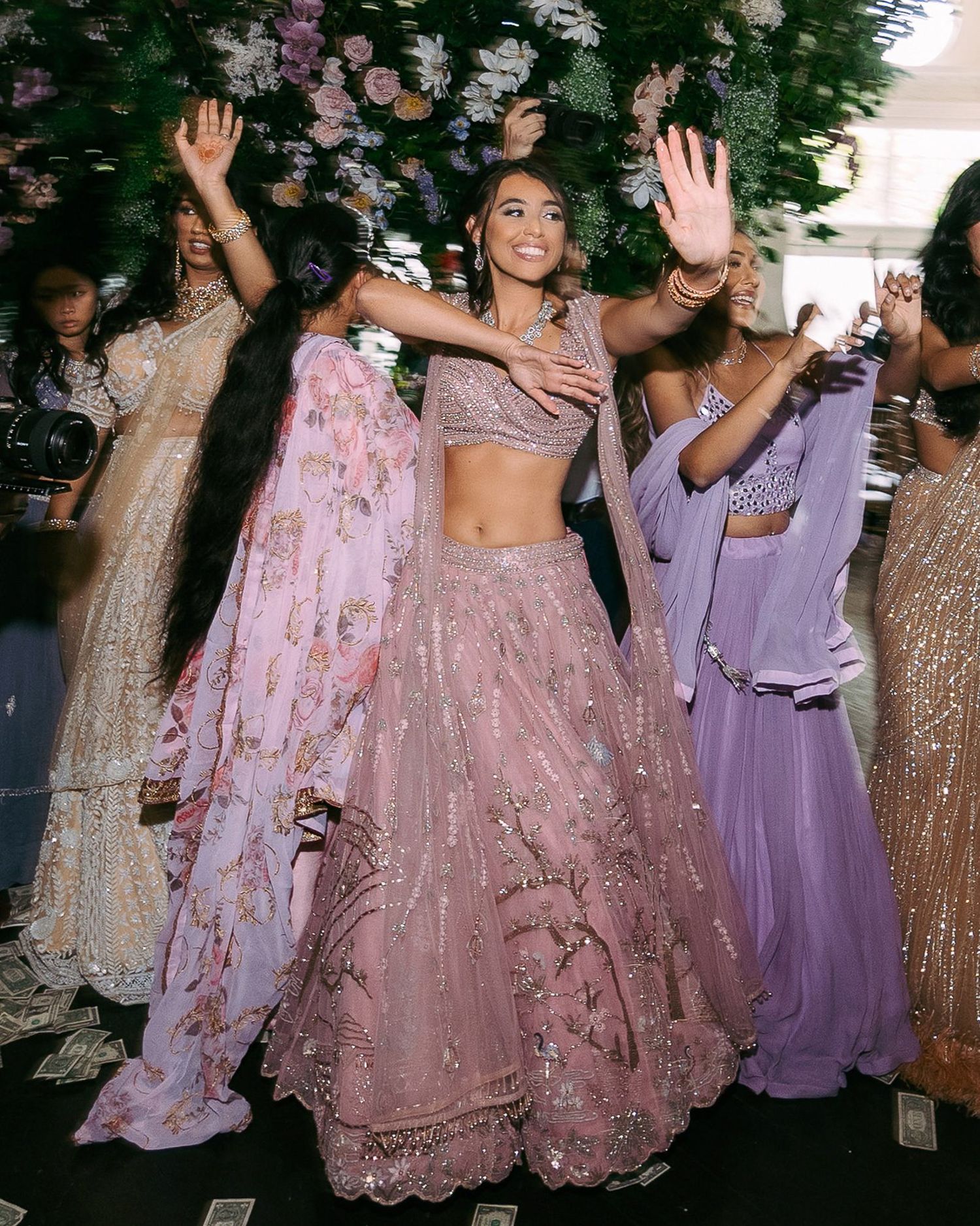 Wedding guests dance and celebrate in pink and purple formal attire during a festive reception.