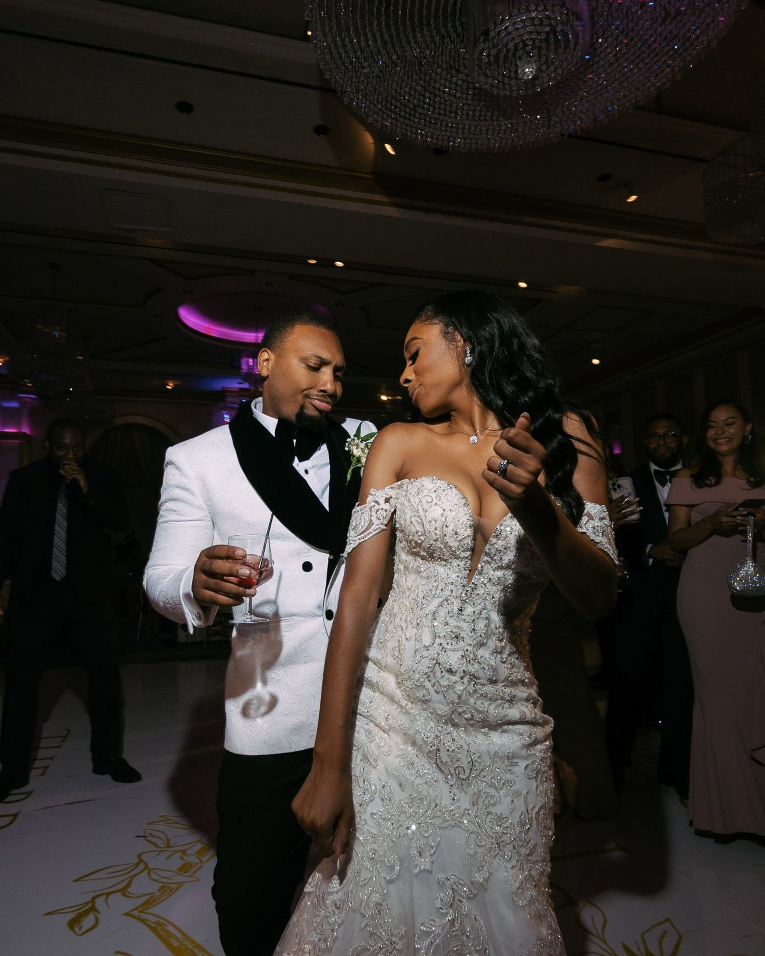 A couple shares an intimate dance moment at a wedding reception with elegant decor and lighting.