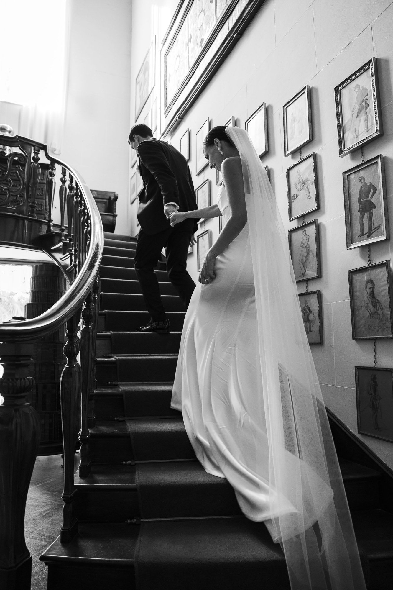 Black and white photo series showing a couple ascending a staircase with artwork on the walls.