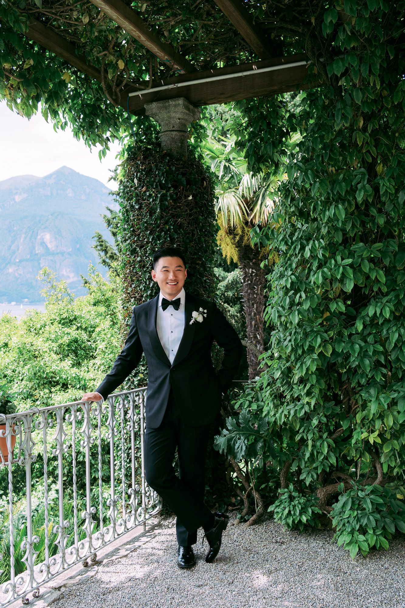 A series of connected photos showing someone in a black tuxedo walking along a vine-covered garden pathway with mountains visible.