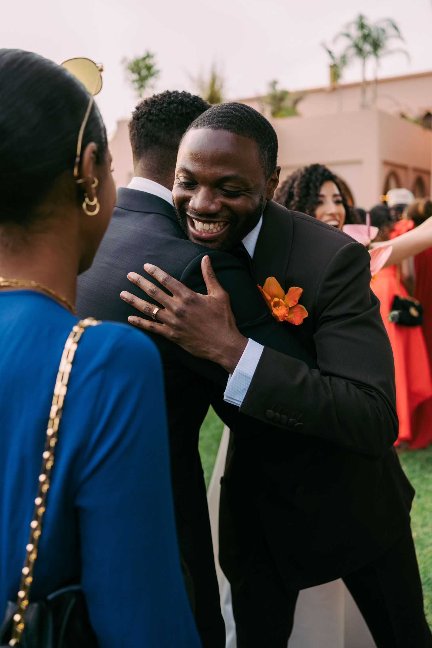 Candid emotional moments shared between wedding guests hugging and laughing together.