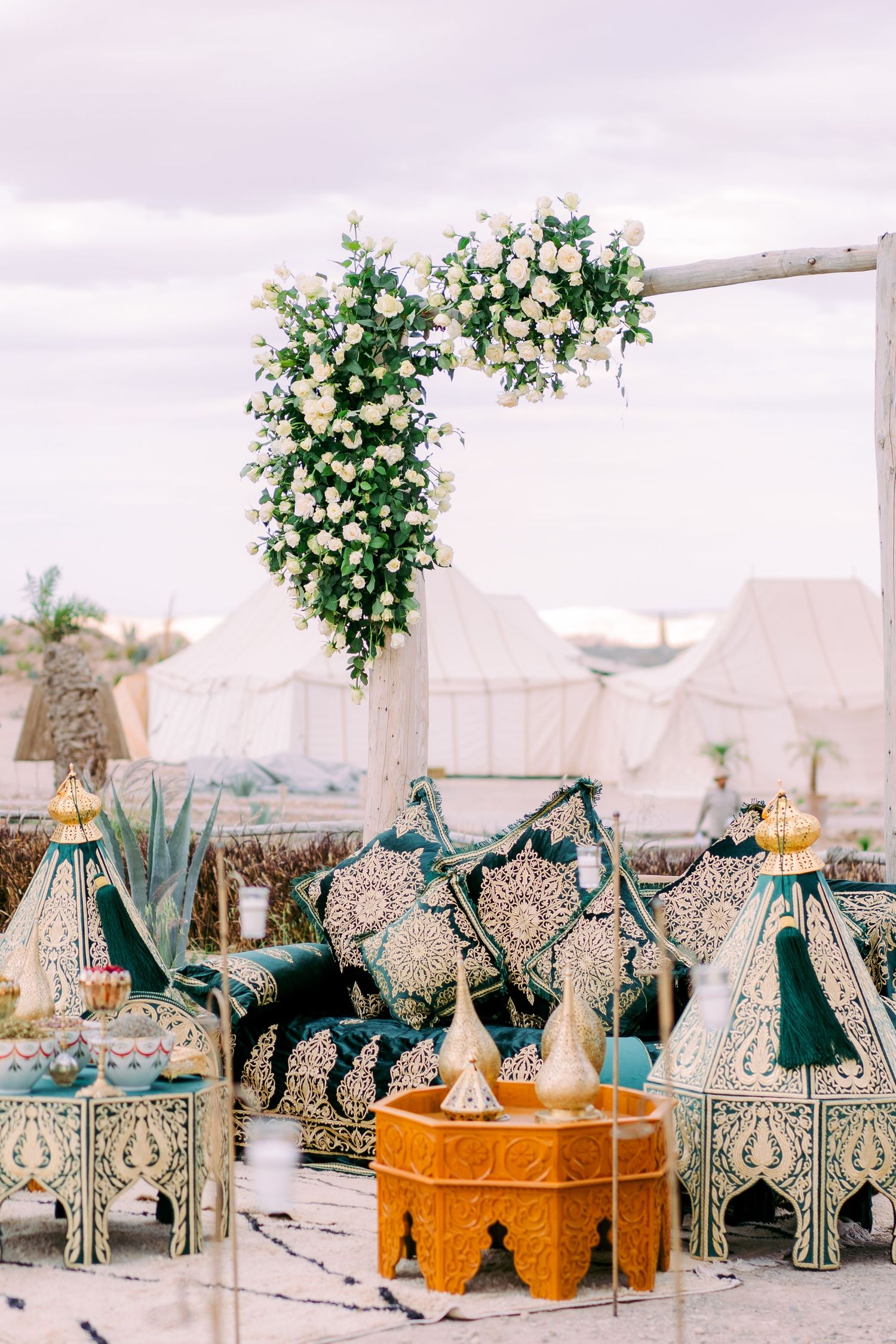 Elegant Moroccan lanterns and floral arrangements displayed at an outdoor desert wedding reception.