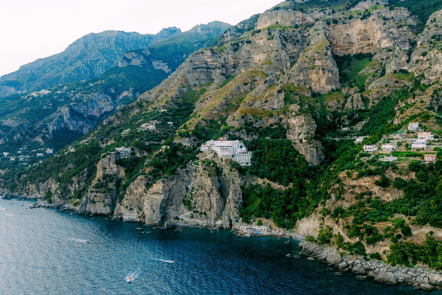 Panoramic view of the rugged Amalfi Coast with steep cliffs, blue Mediterranean waters, and coastal villages in Italy.