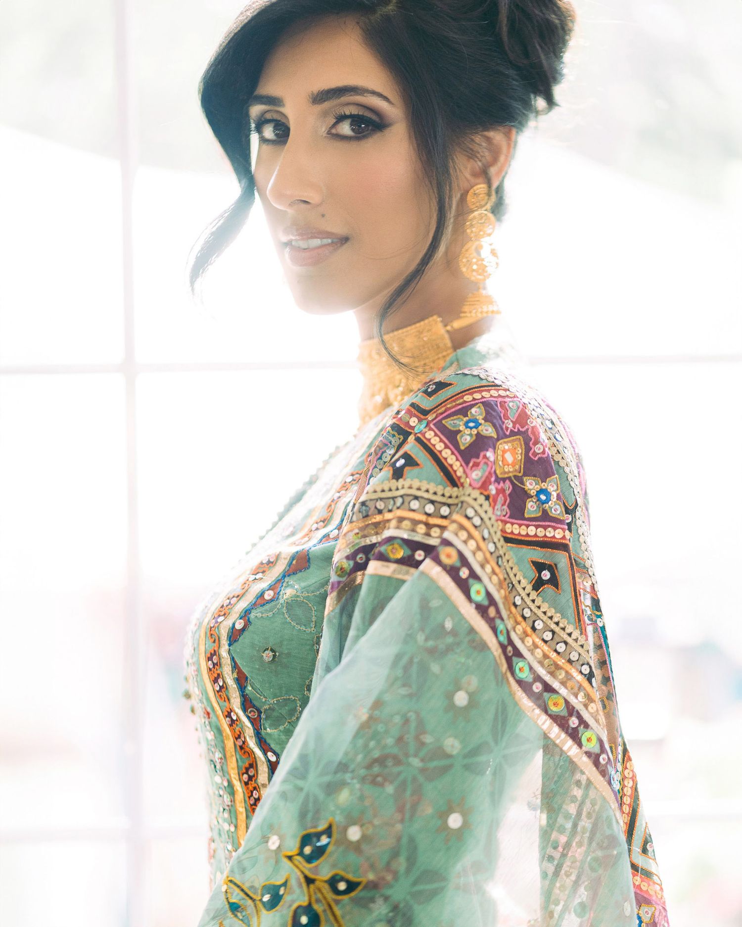 Woman wearing ornate mint green traditional Indian saree with detailed embroidery and embellishments.