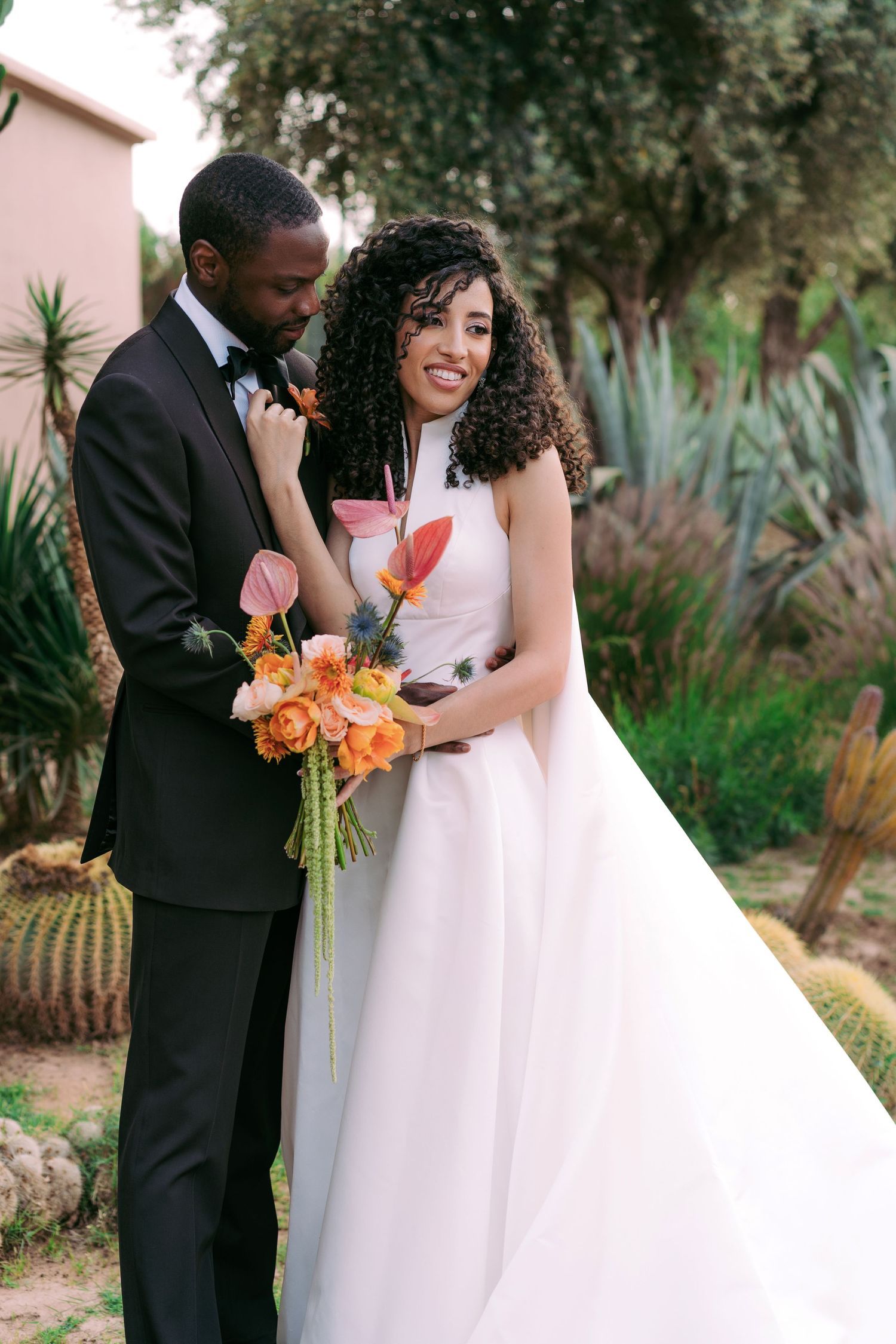 A couple shares a romantic moment in a garden setting with tropical plants and colorful flowers.