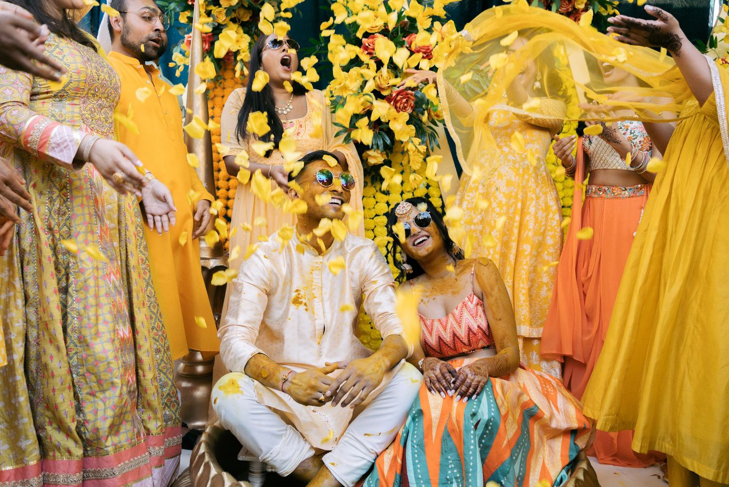 Wedding guests participate in a joyful Indian Haldi ceremony with yellow turmeric powder and traditional attire.
