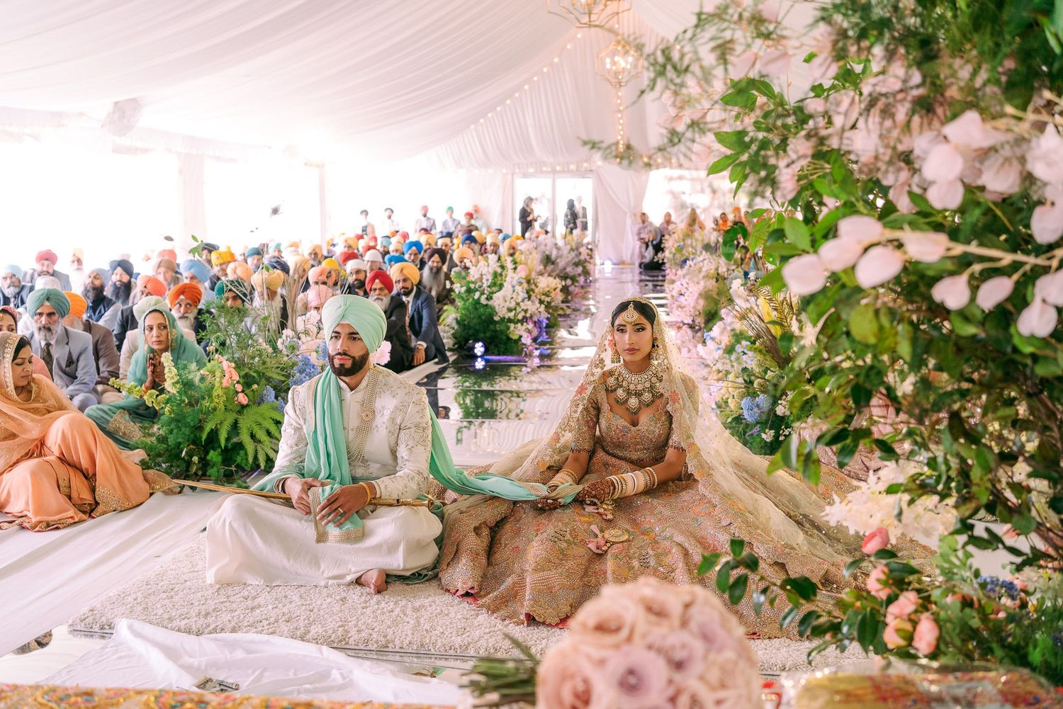 Elegant wedding Indian  ceremony setup with pink and white floral decorations in an outdoor garden setting.