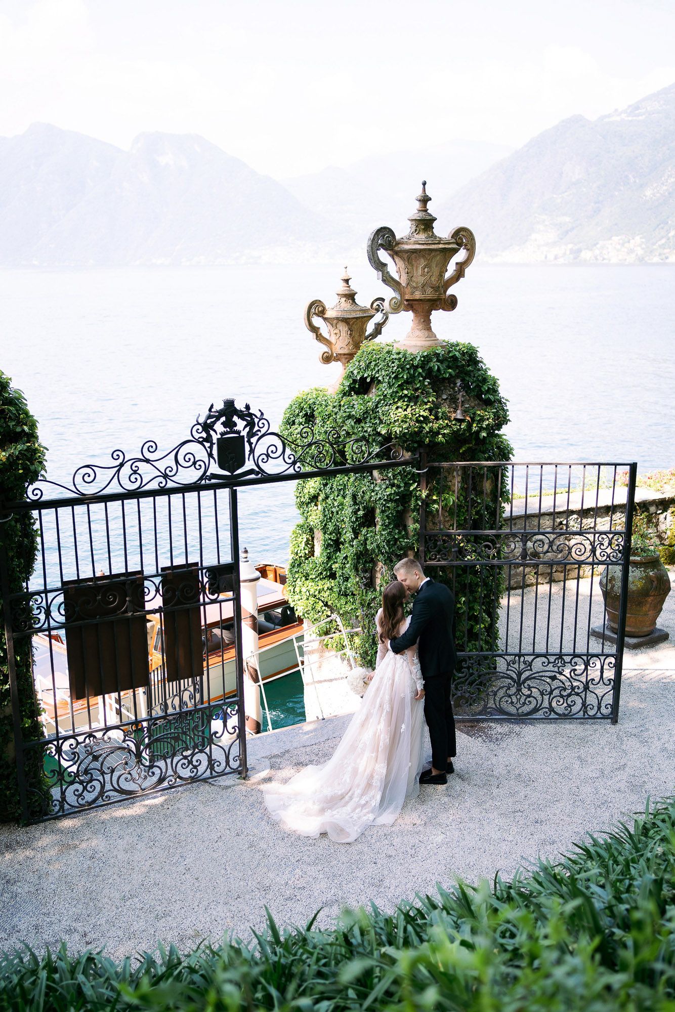 A romantic scene overlooking Lake Como from an ornate terrace with wrought iron railings and decorative stone urns. wedding photographer