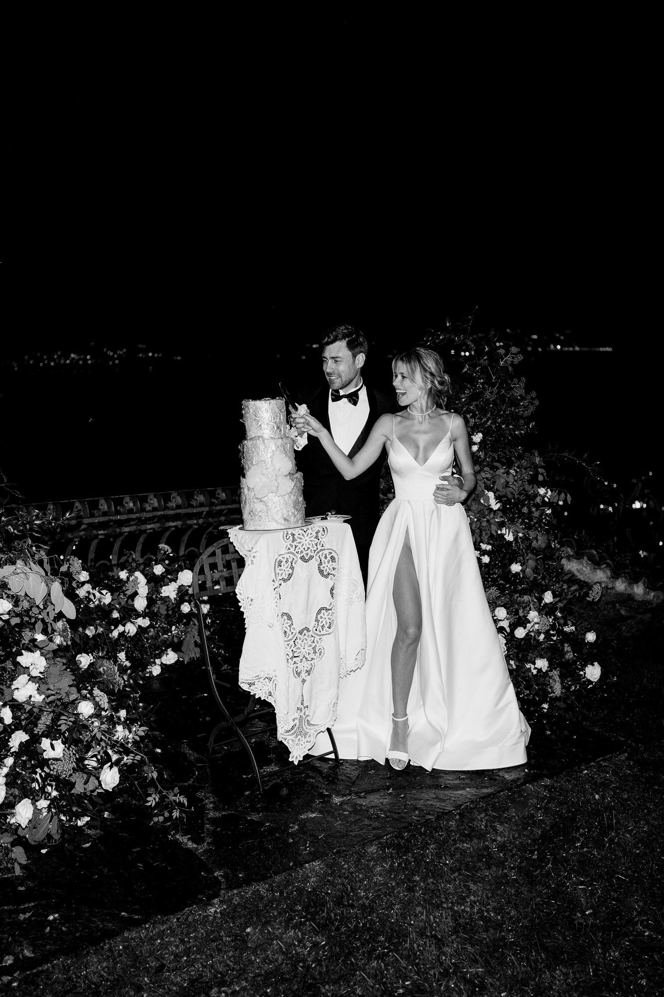 A black and white photo series shows people in white dresses sitting among garden flowers at night.