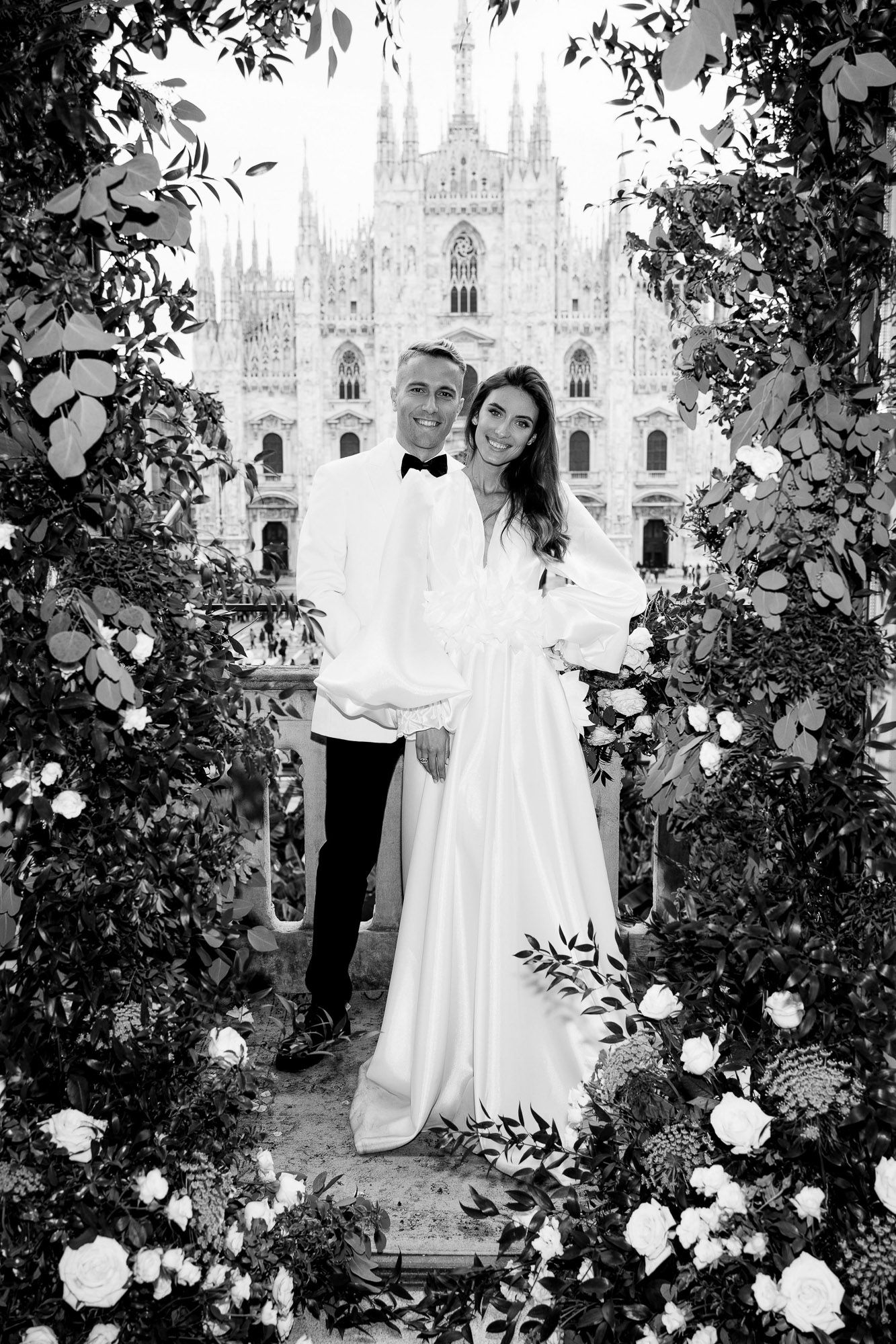 Black and white wedding photos in front of Milan Cathedral with white roses framing the romantic scene.