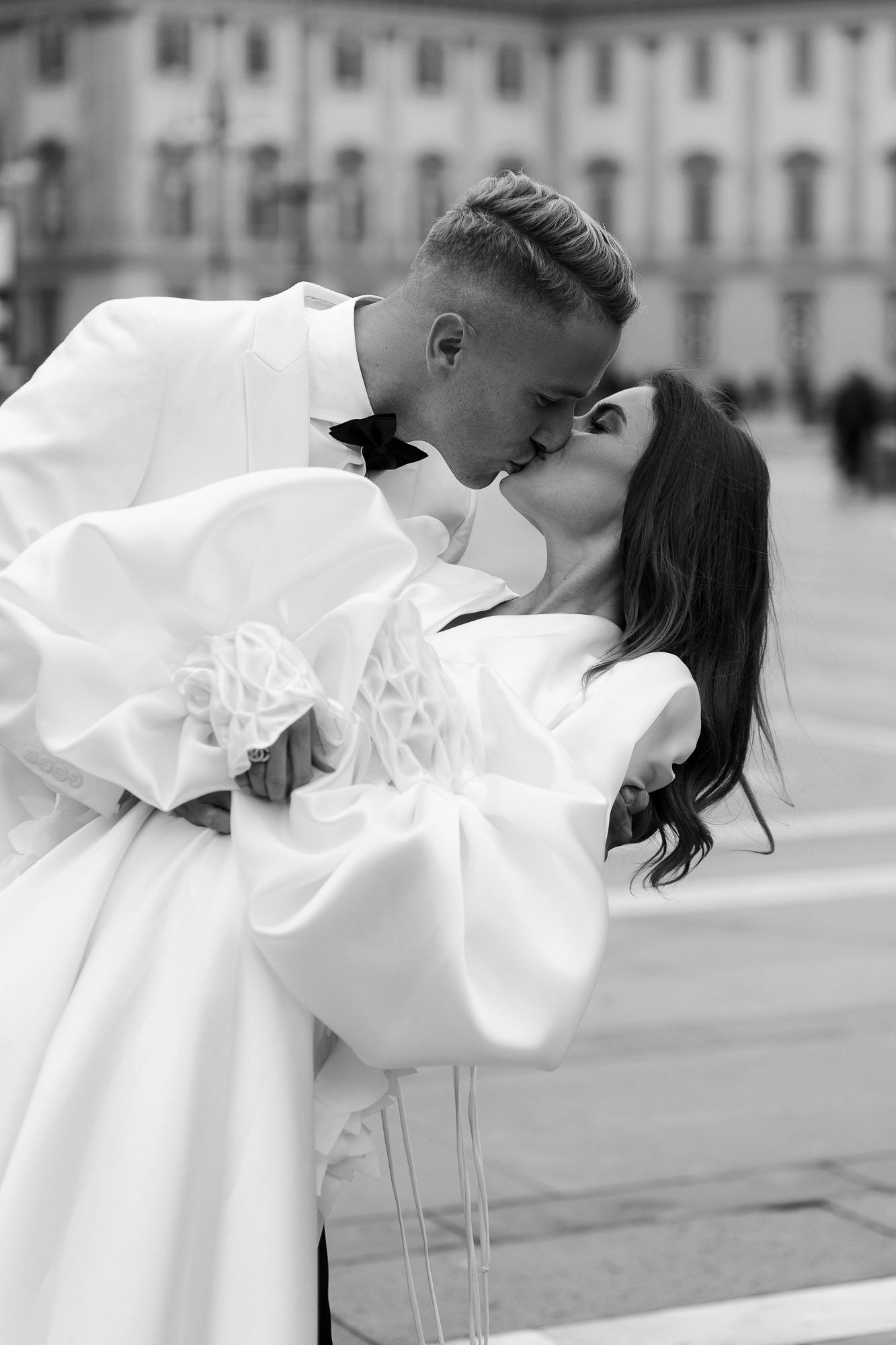Black and white romantic wedding photo series showing a couple in intimate embraces with flowing white dress details.