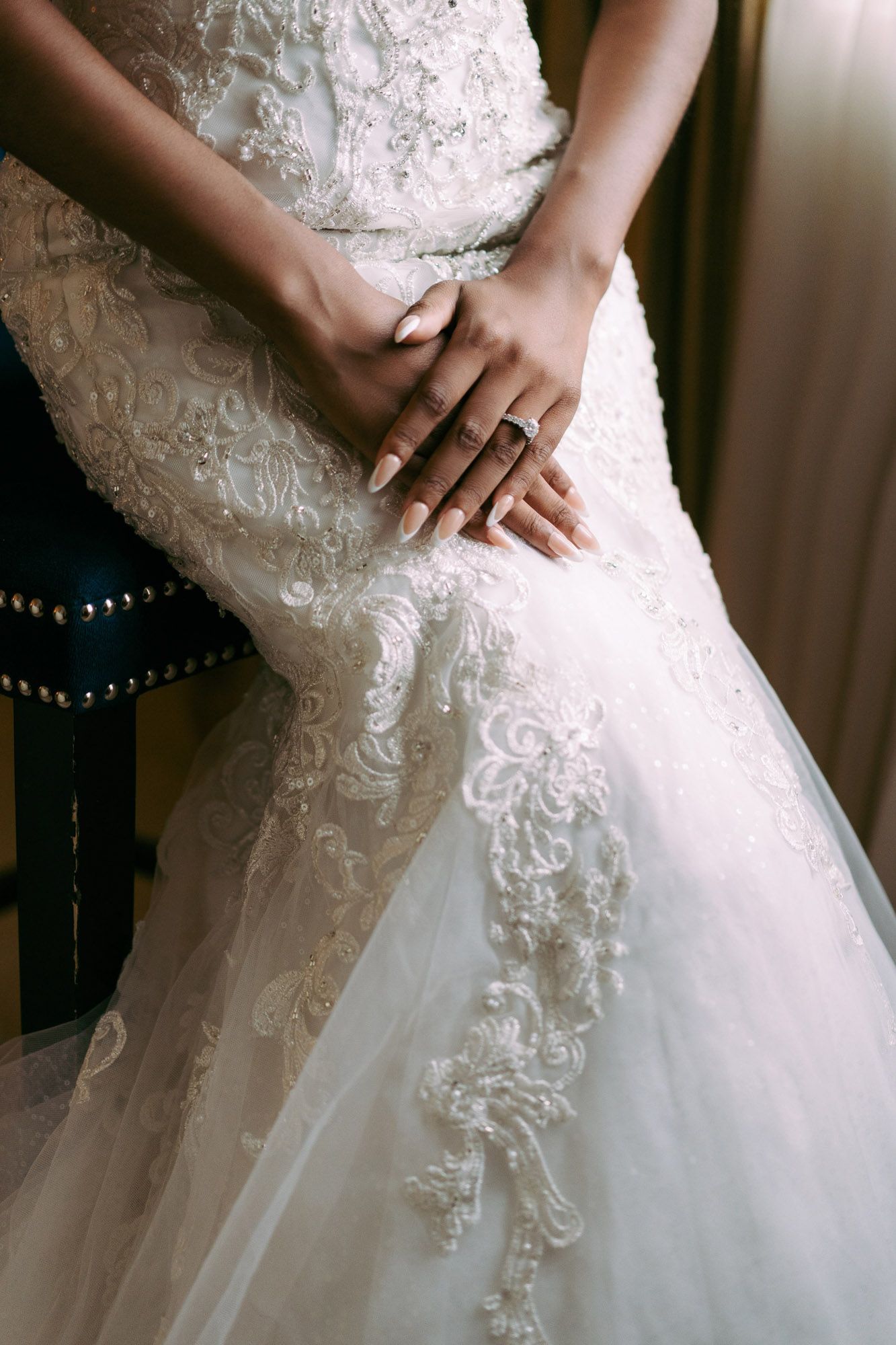 Close-up details of a white wedding dress showing intricate lace embellishments and delicate beadwork on the bodice.