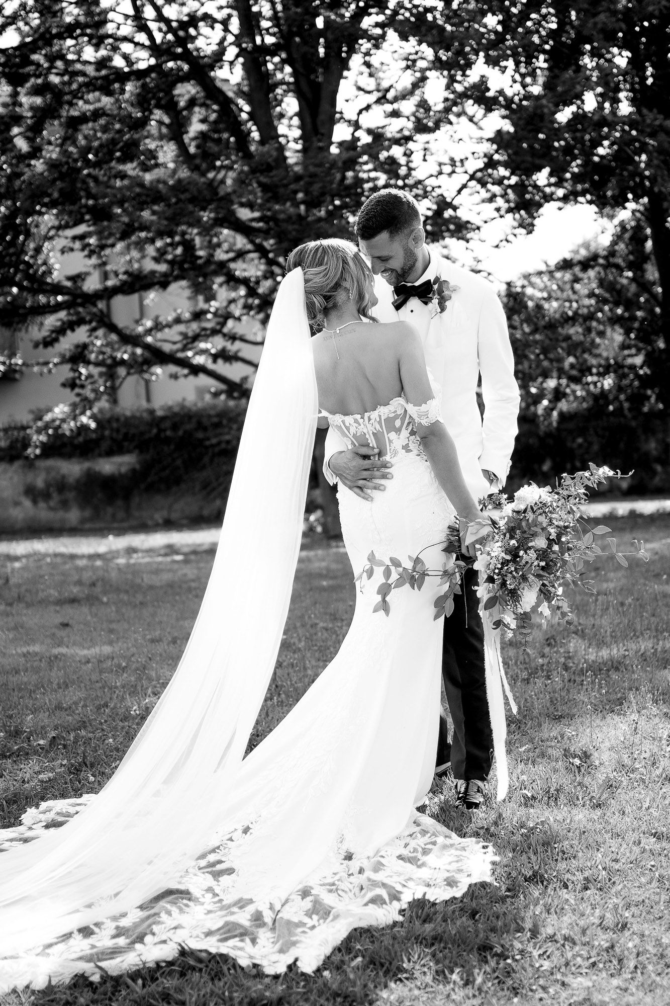 Black and white wedding photos show romantic moments between newlyweds in a garden setting with flowing white dress.