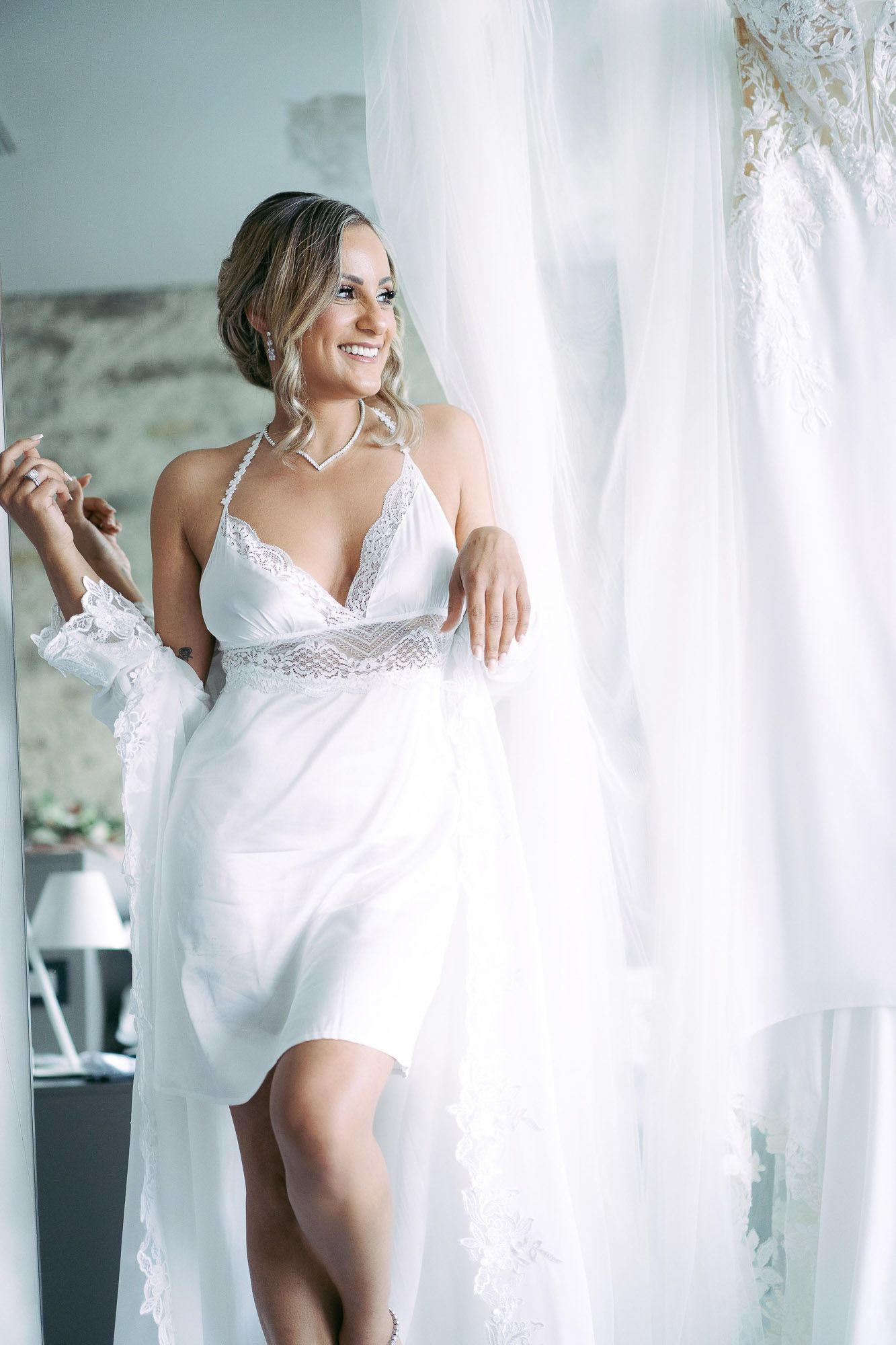 Artistic boudoir photo series showing figure in white lace lingerie against bright window light and sheer curtains.