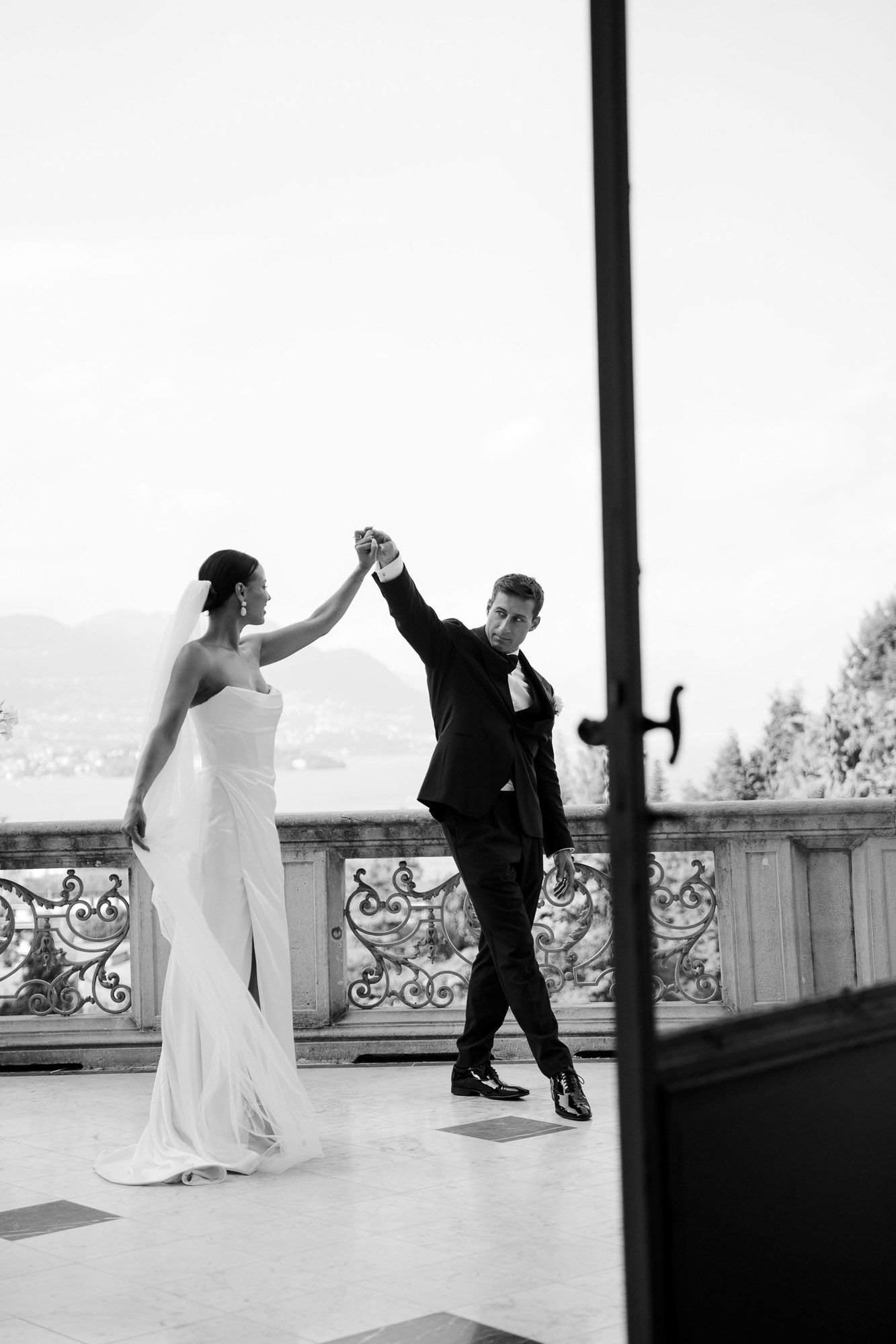 A sequence of black and white photos showing a couple dancing together on a balcony with scenic views.
