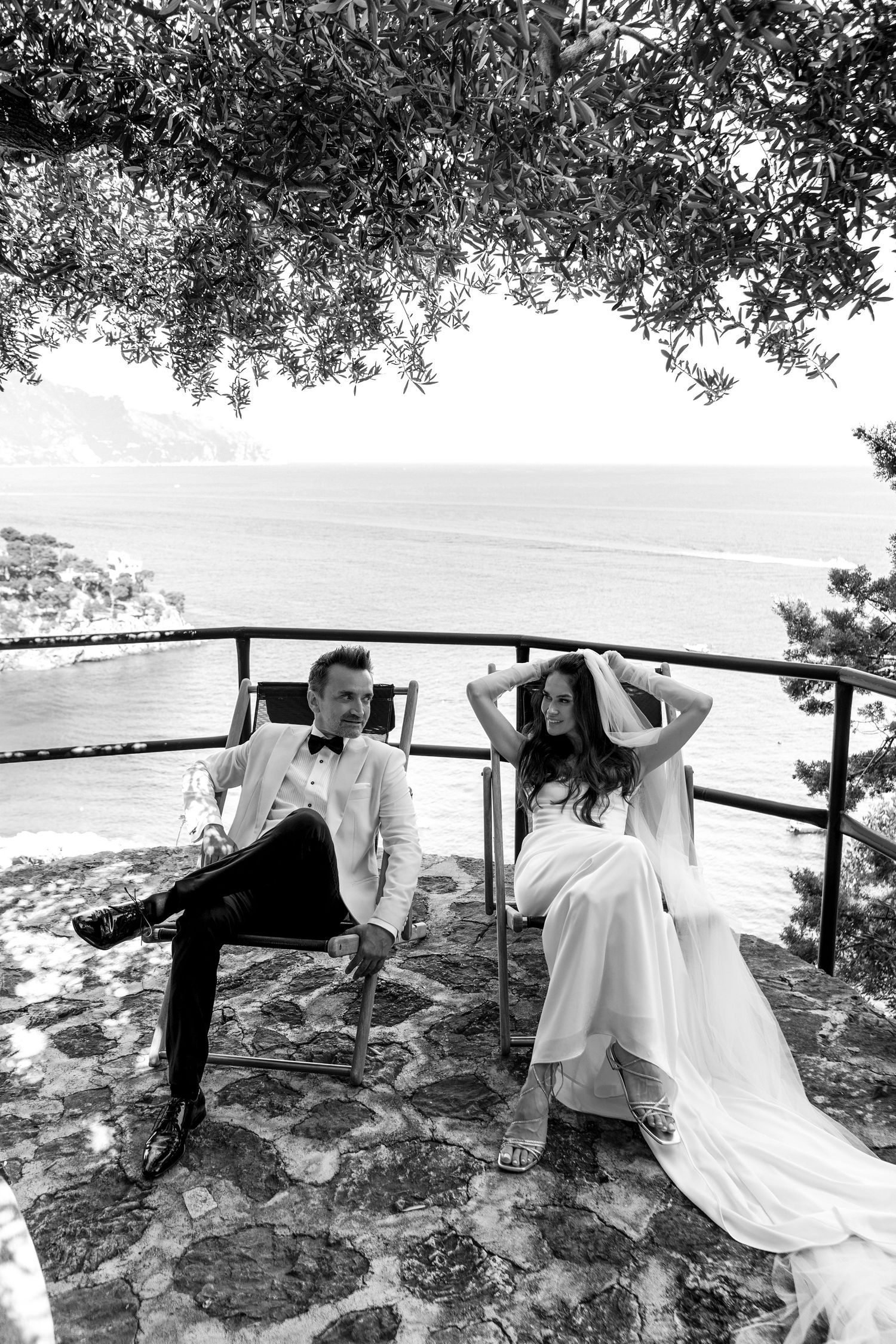 Black and white photo series showing a couple in wedding attire playfully running with flowing white fabric outdoors.