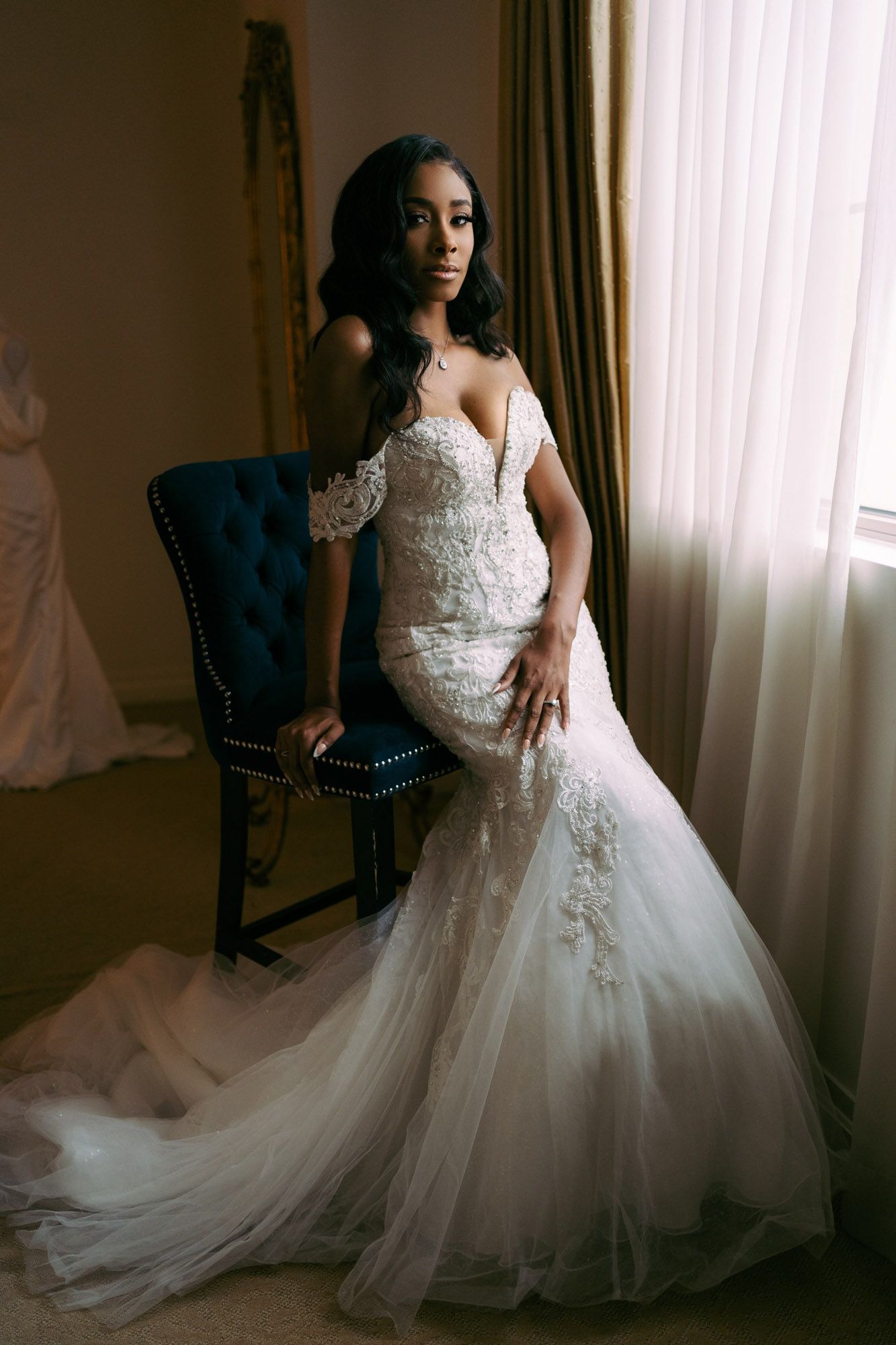 Elegant bride in lace ballgown poses gracefully near window in sequence of romantic bridal portraits.