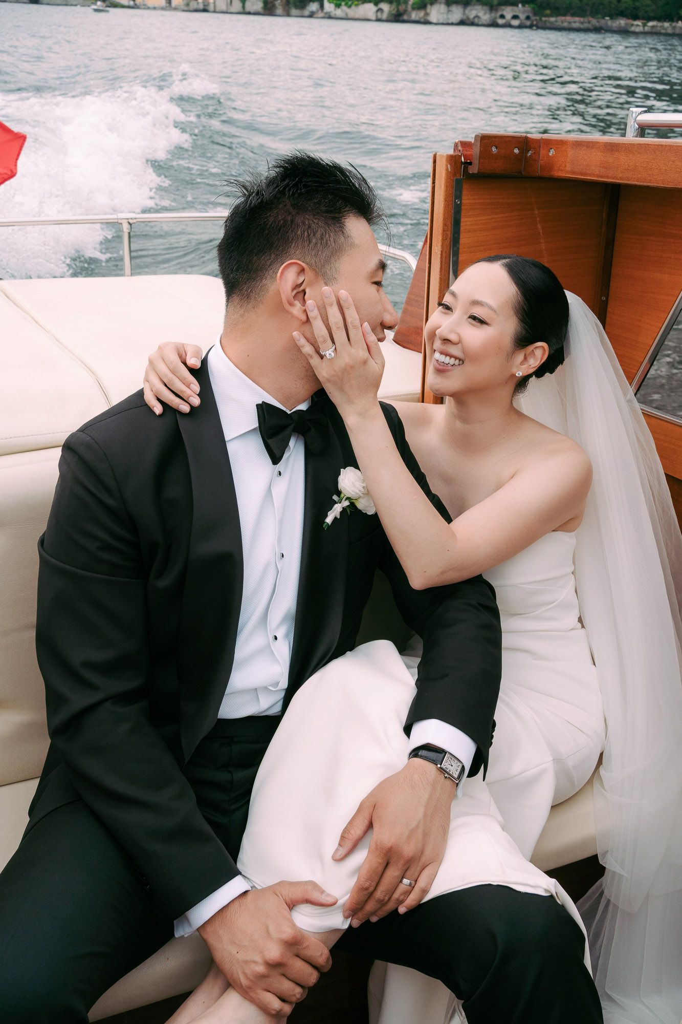 Intimate wedding moments captured on a luxury boat with mountains and water in the background.