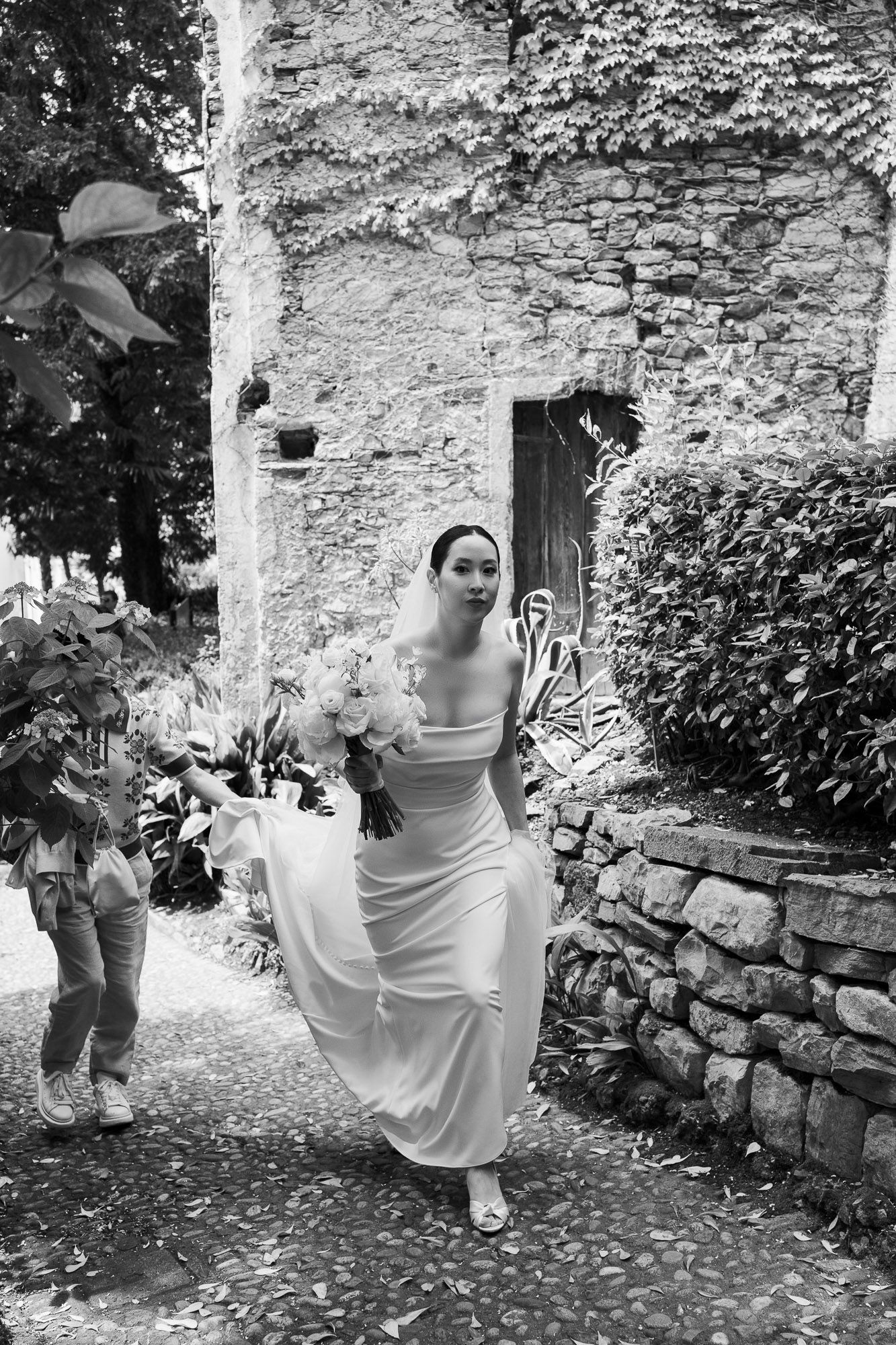 A sequence of black and white photos shows a figure playfully jumping and posing along a rustic stone wall.