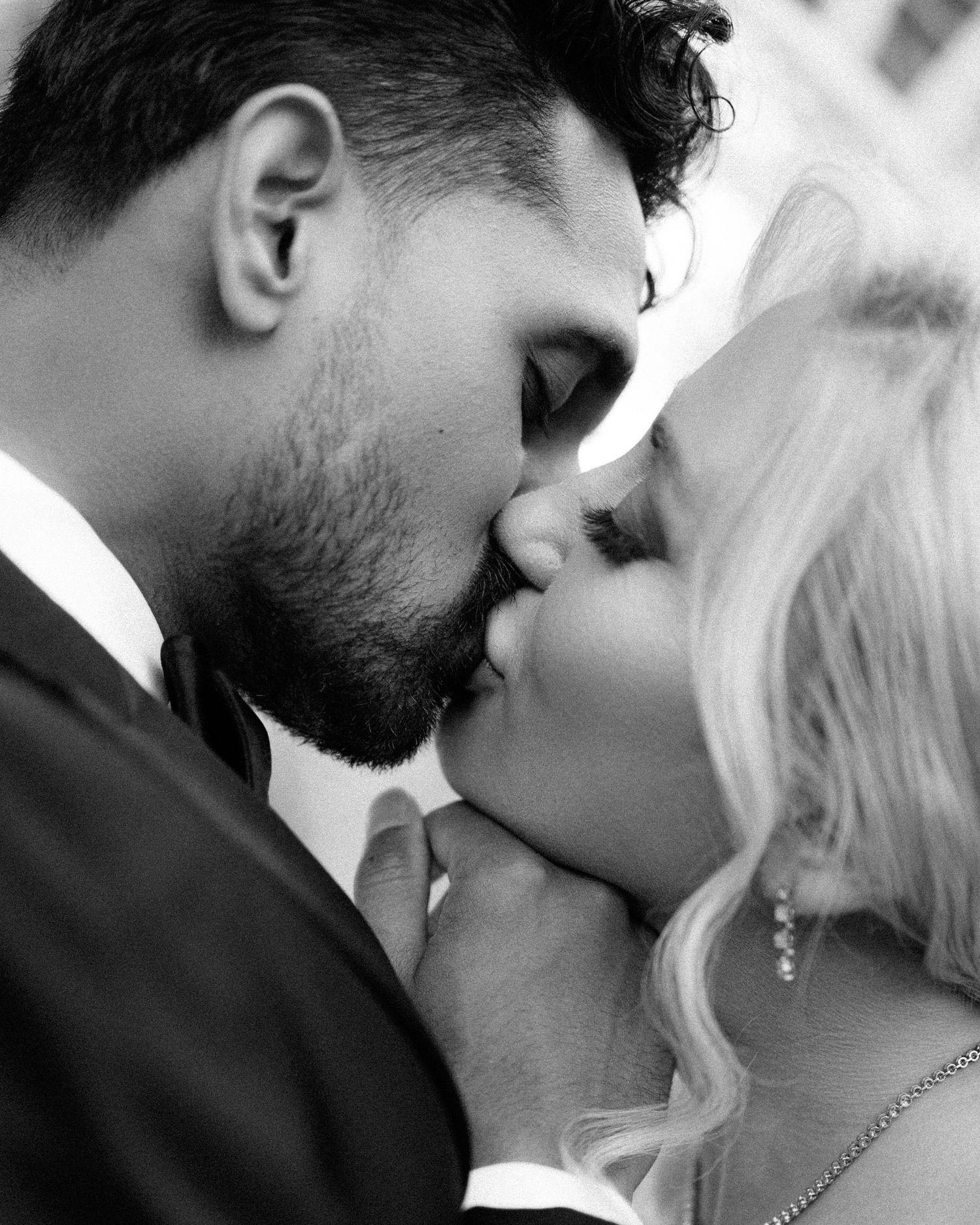 A romantic couple shares an intimate kiss in a series of black and white photographs showing different angles.
