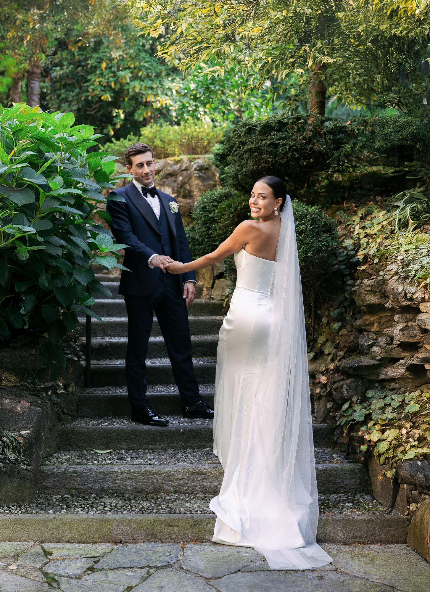 A romantic wedding photoshoot sequence in a garden setting with stone pathways and lush greenery.