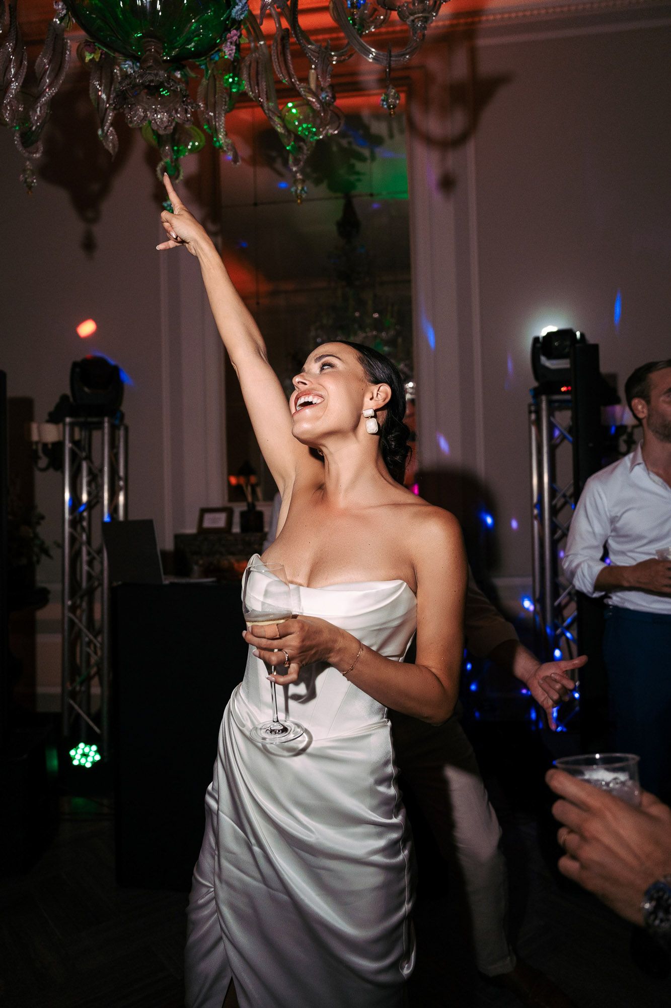 Partygoers dancing and celebrating in a dimly lit venue with festive decorations and colored lighting.