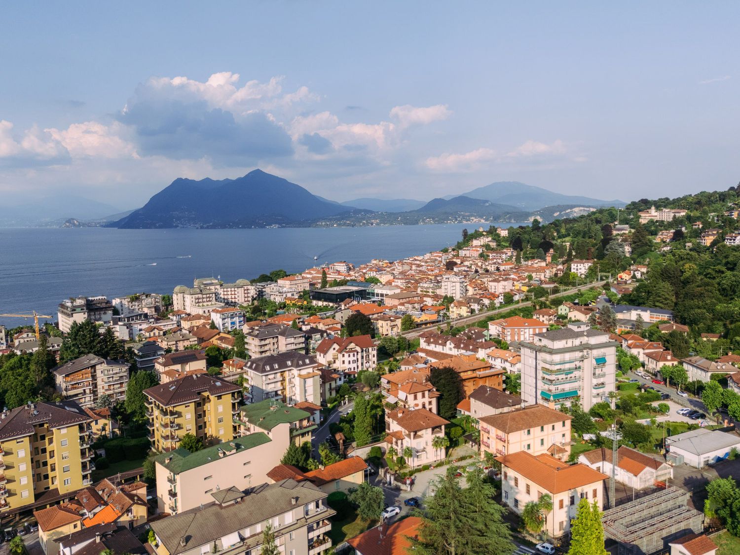 Panoramic view of a coastal Mediterranean town with colorful buildings nestled along hillsides overlooking the sea.