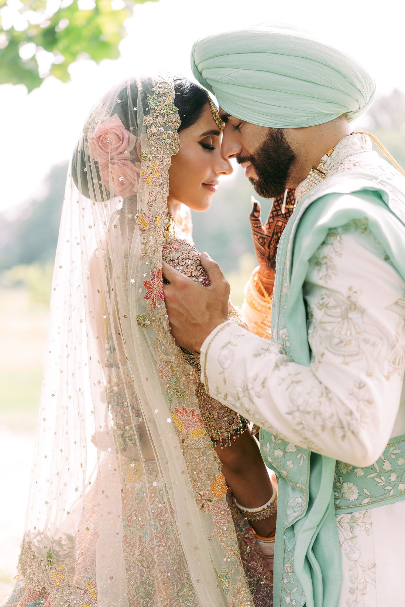 Romantic Sikh wedding photoshoot outdoors with couple in traditional white and mint green ceremonial dress.