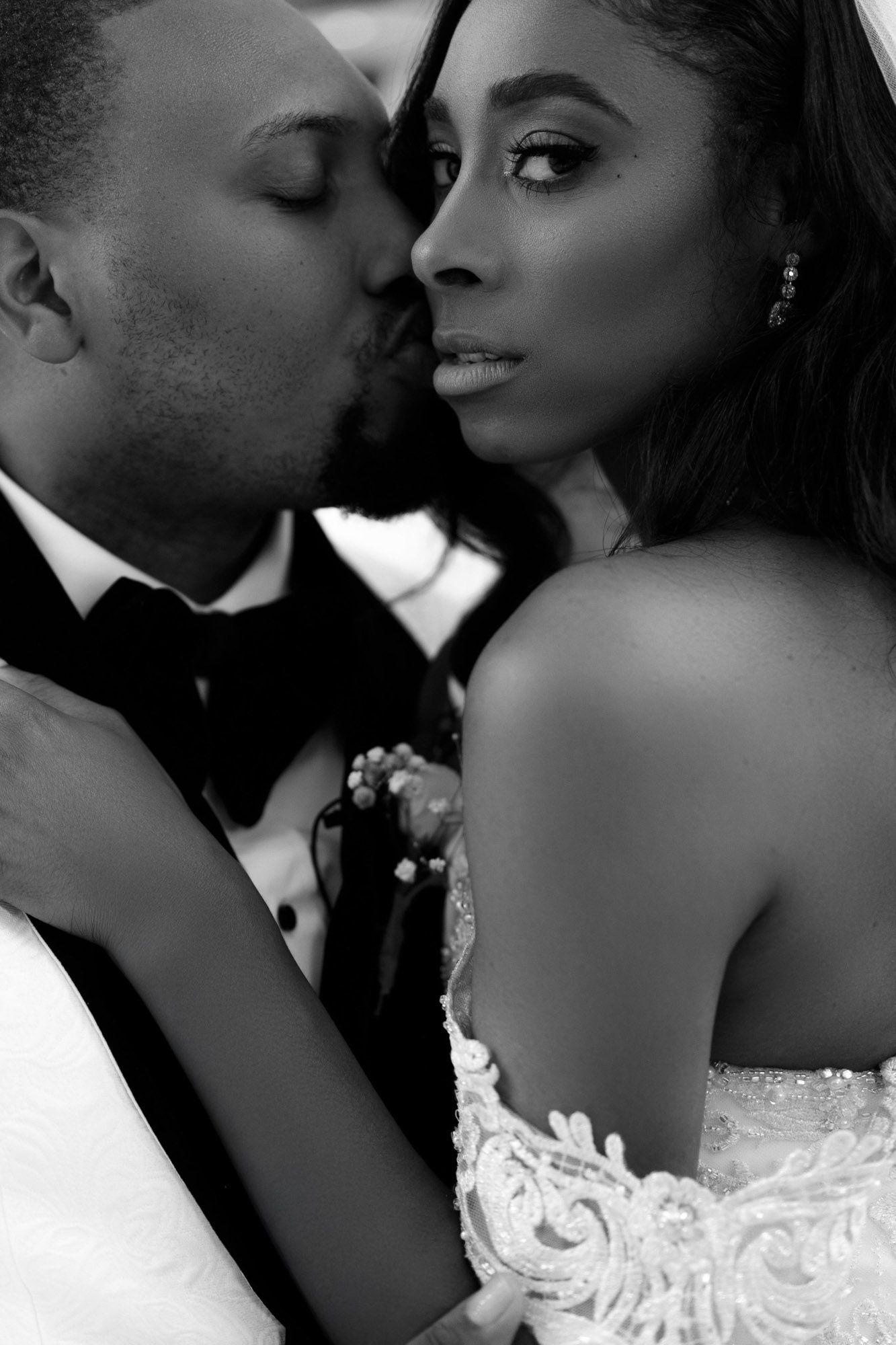 A romantic black and white wedding photo series showing intimate moments between newlyweds in formal attire.