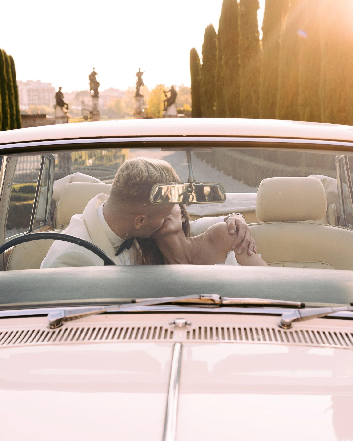 Couple shares intimate moments in vintage car interior during sunset golden hour.