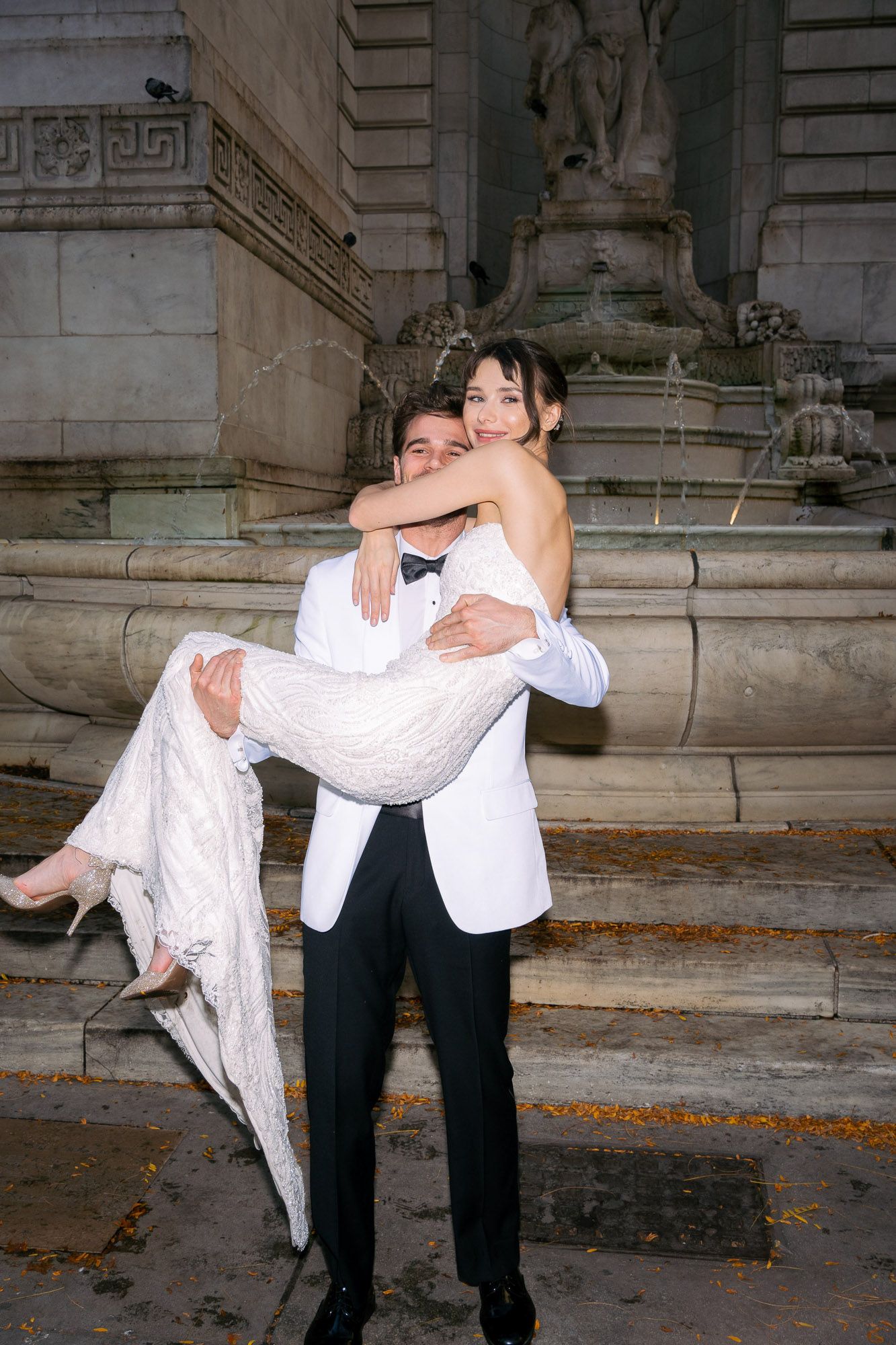A romantic couple recreates a dance lift sequence on stone steps with autumn leaves scattered around them.