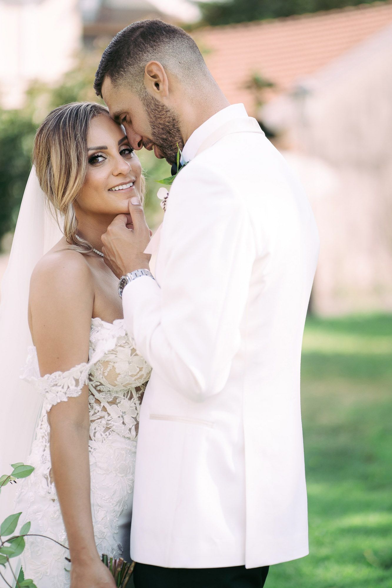 A romantic wedding couple shares intimate moments in a garden setting with soft natural lighting.