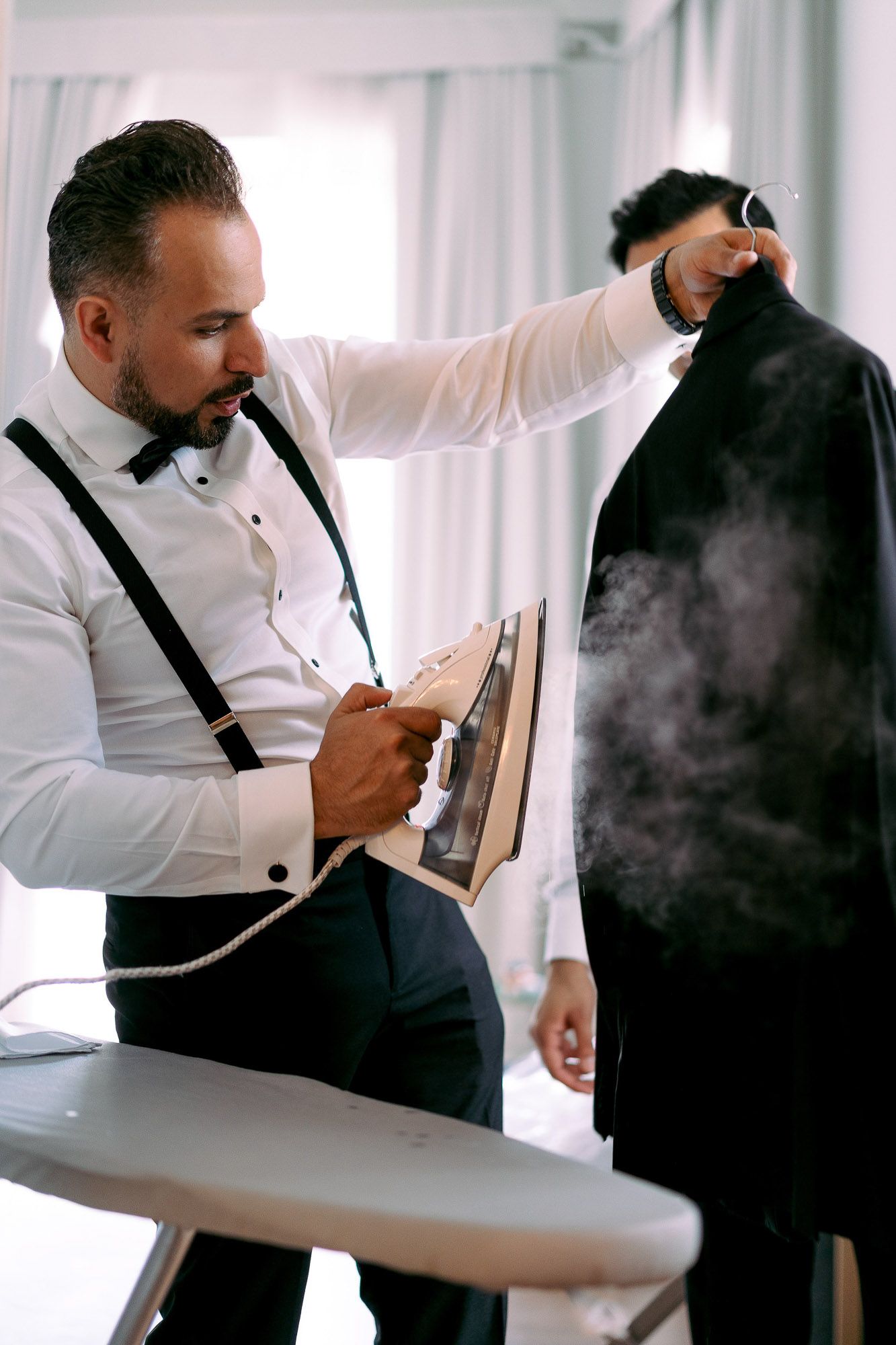 A sequence of images showing someone in formal attire steaming clothes with a handheld steamer.