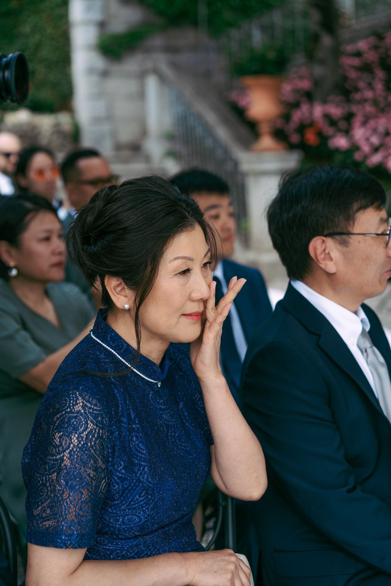 A sequence of photos showing a guest in a navy blue lace dress becoming emotional during a wedding ceremony.