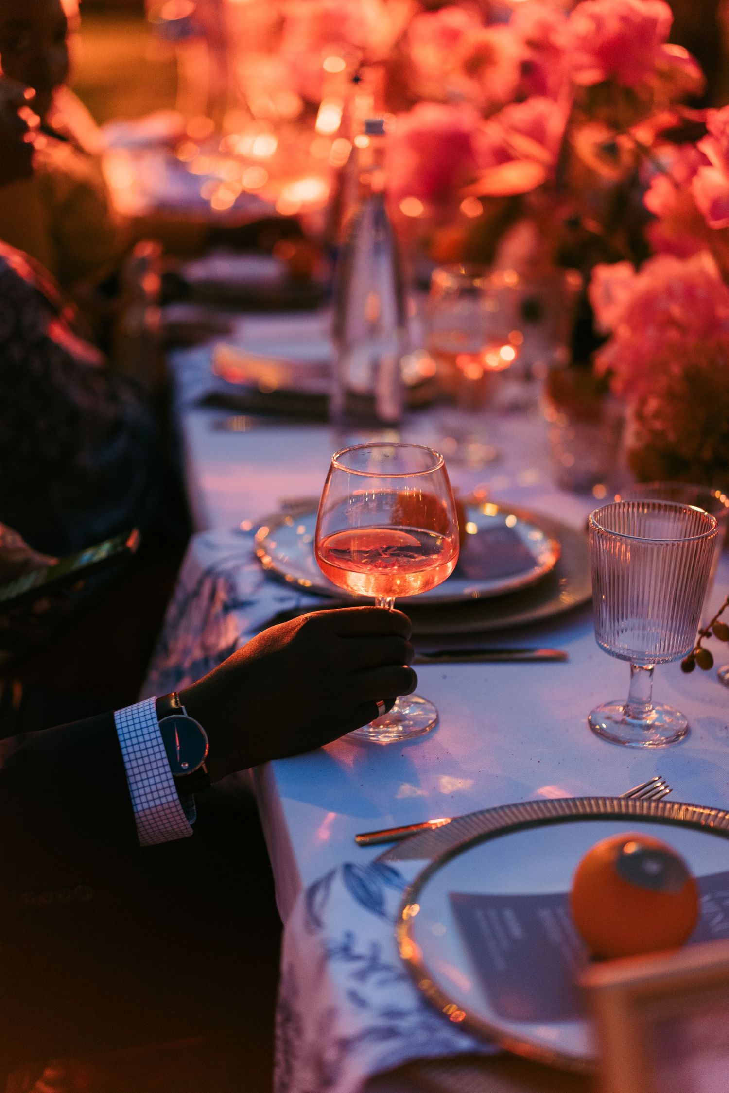 Elegant table setting with wine glasses and place settings illuminated by warm lighting.