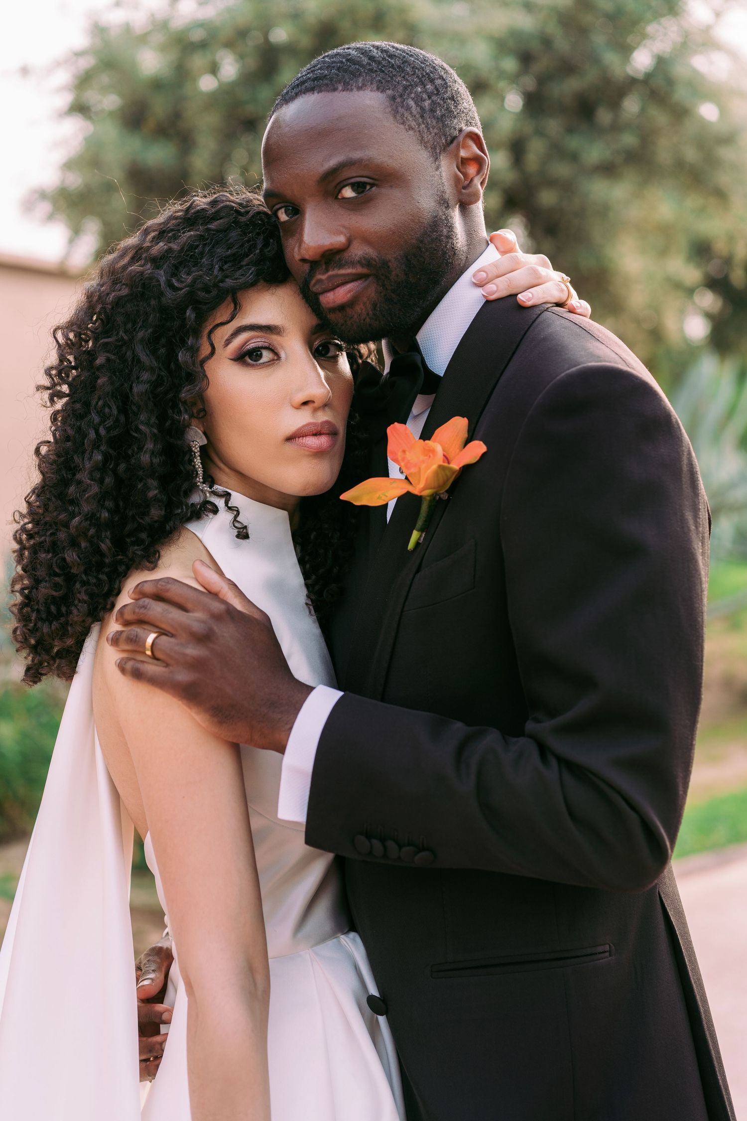 Intimate wedding portrait with orange floral accents and formal attire.