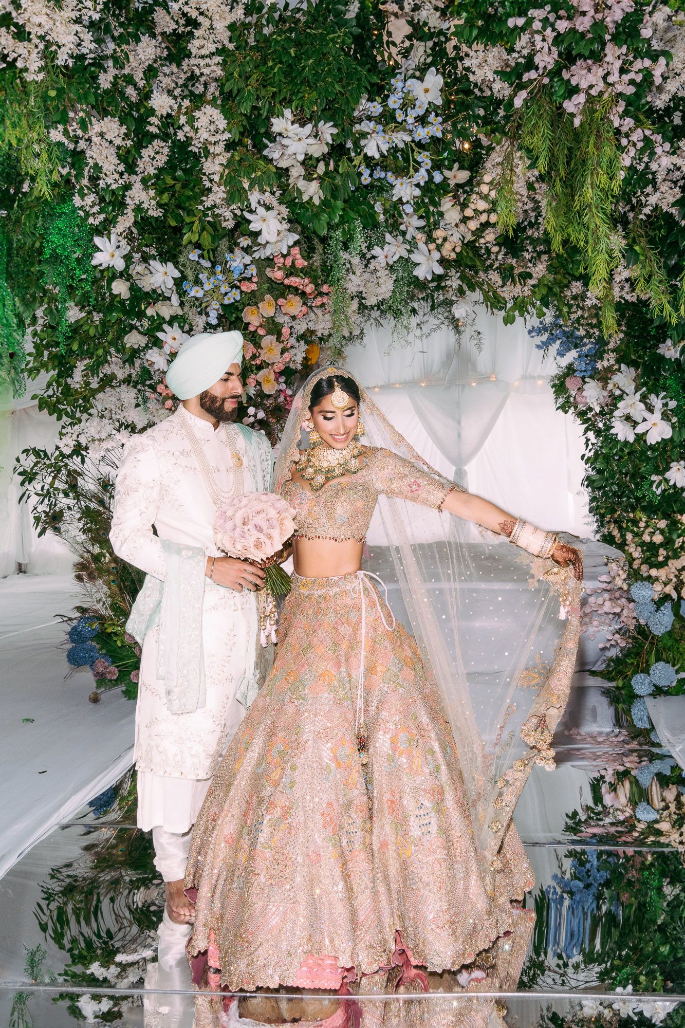 A sequence of photos showing a couple in elegant attire twirling under a floral arch decorated with pink blossoms.