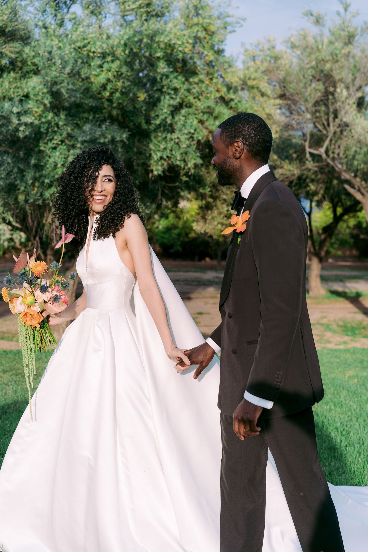 Elegant wedding couple walking through a lush garden setting.